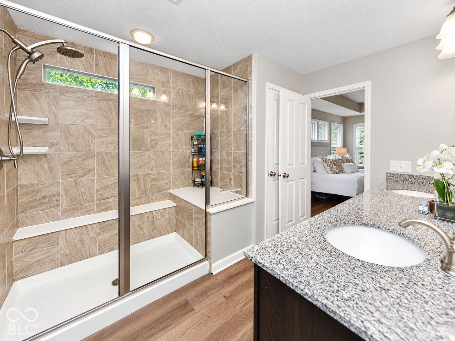 Walk-in shower with natural stone-look tiling, rain showerhead, and built-in bench