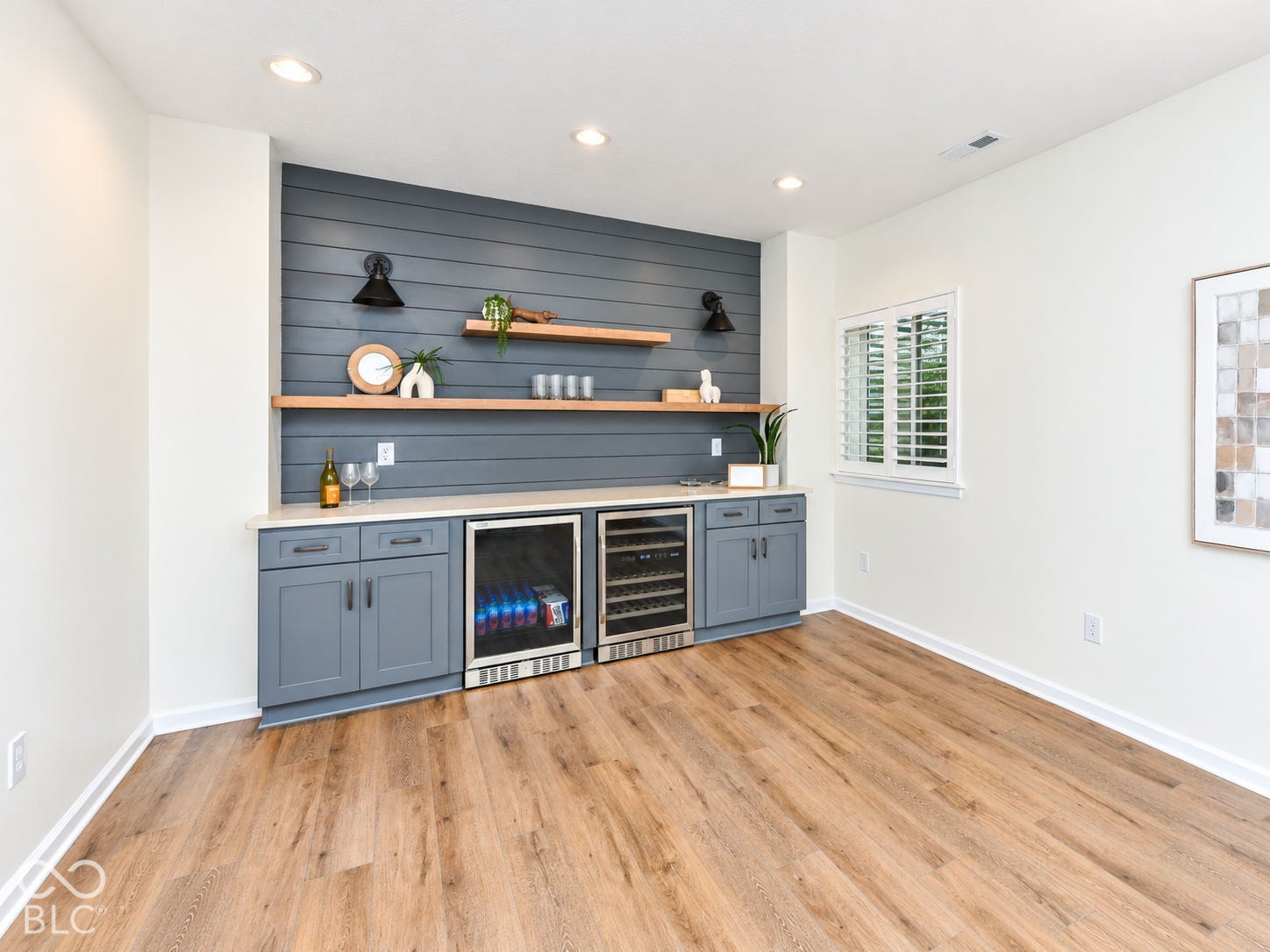 Wood-finish flooring, recessed lighting, and a built-in wet bar with a light-toned countertop