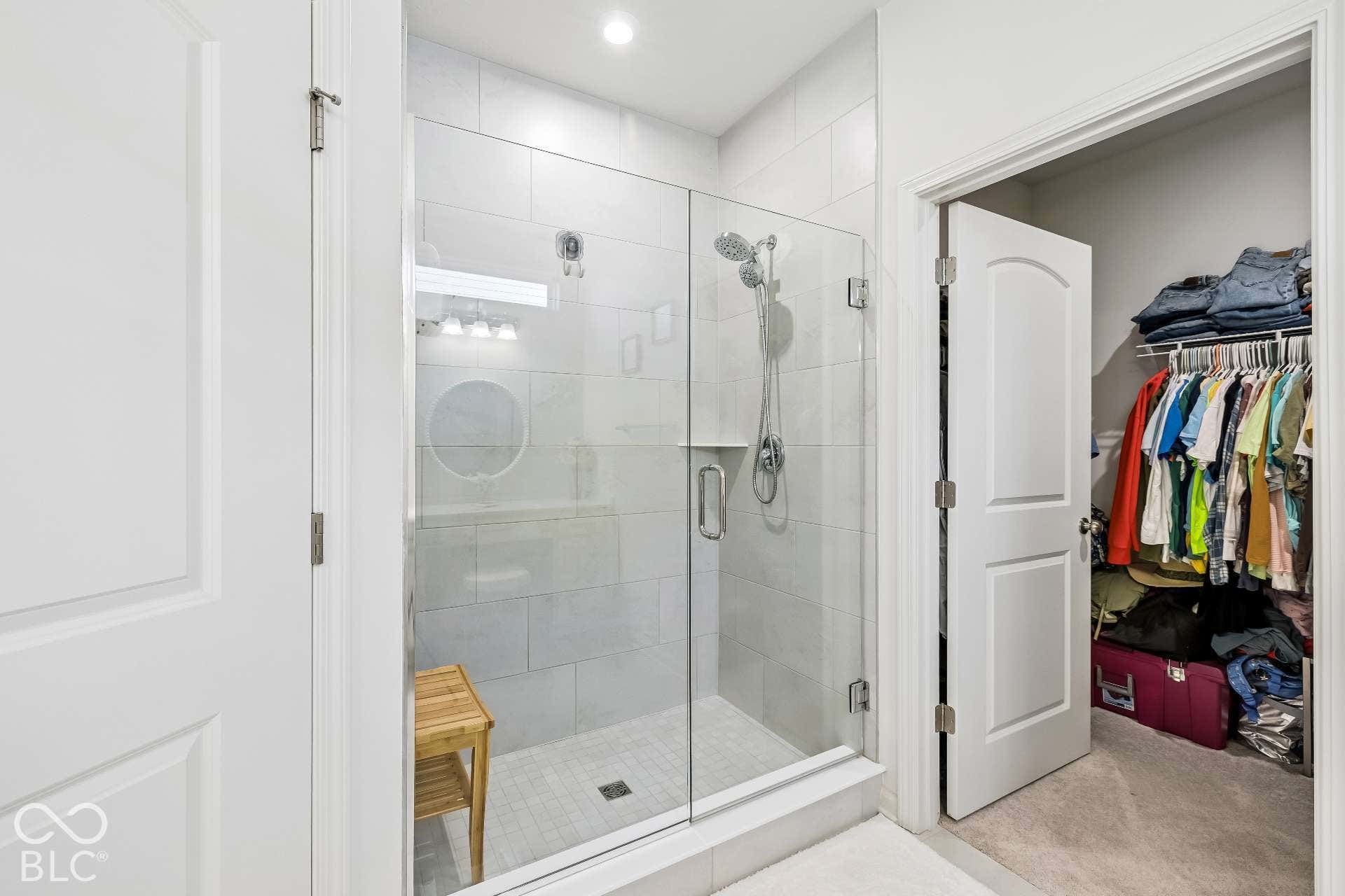 Glass-enclosed shower with subway tile surround, multiple shower heads, and built-in shelving