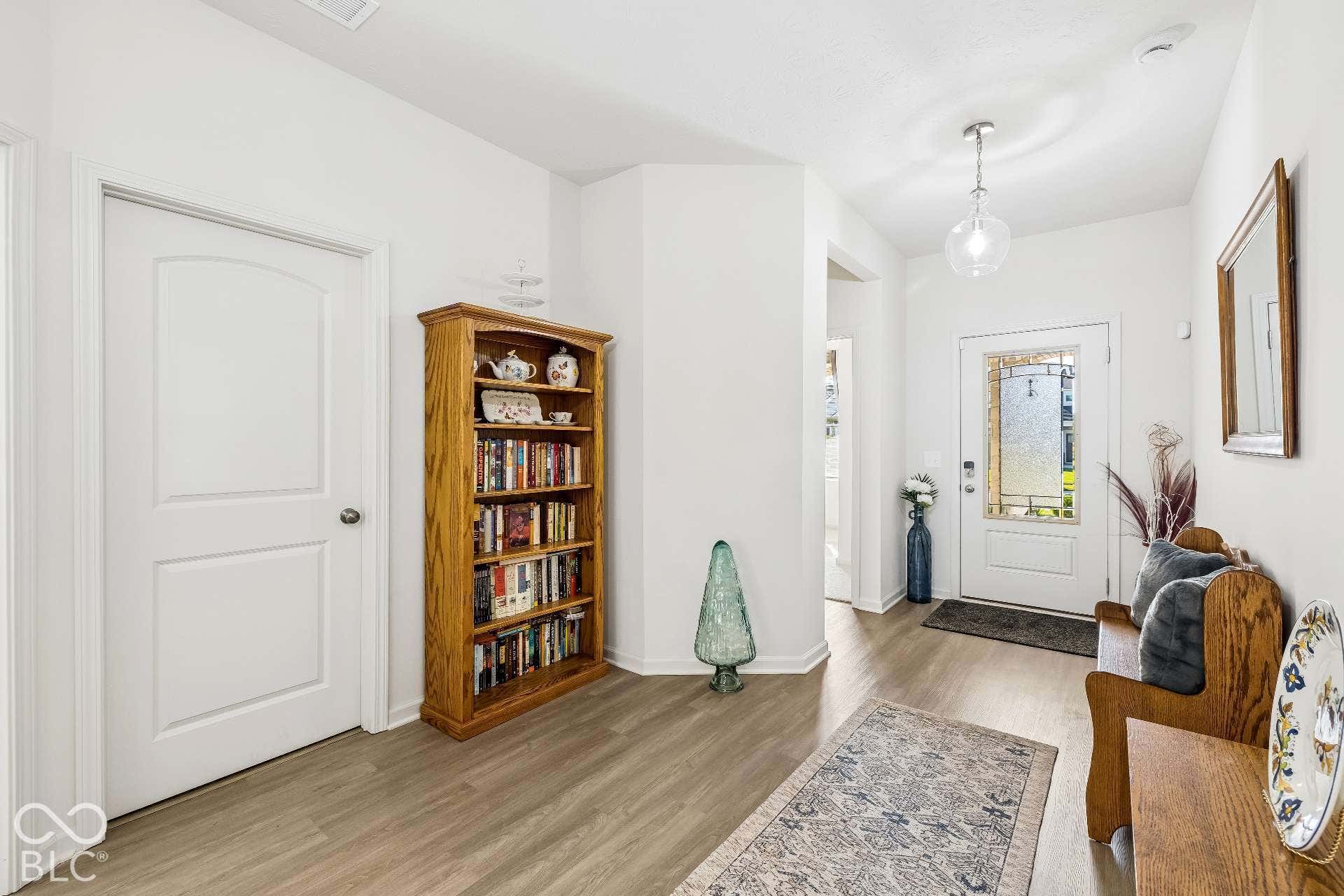 Wood-finish flooring throughout, white interior doors, and a clear glass pendant light fixture