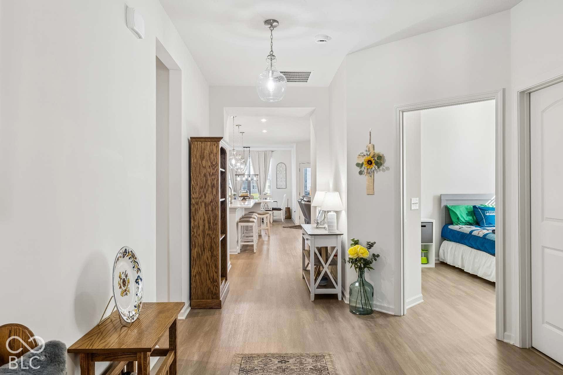 Wood-finish flooring throughout, with a recessed lighting fixture and a clear glass pendant light