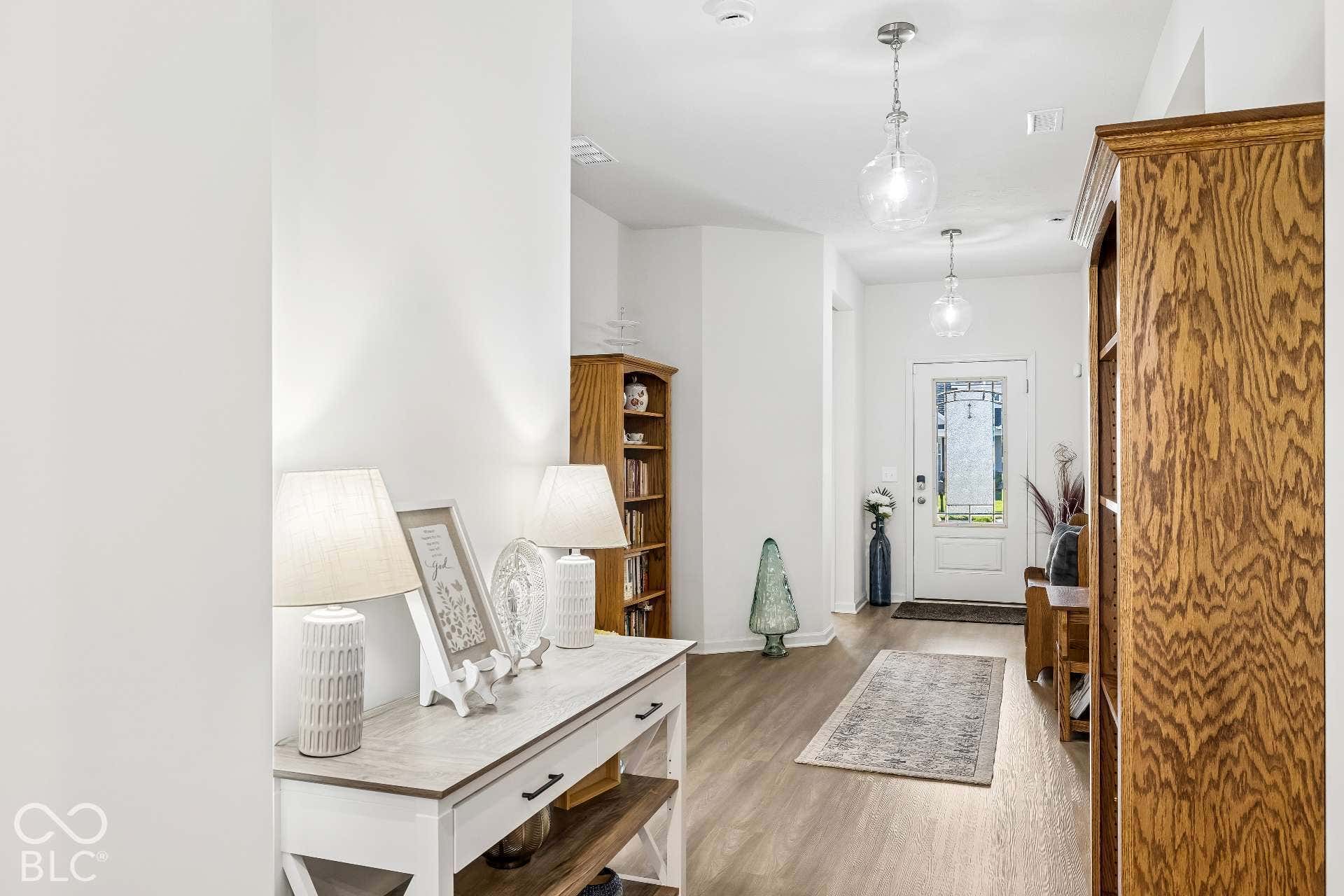 Wood-finish flooring, white walls, and a white front door with decorative glass