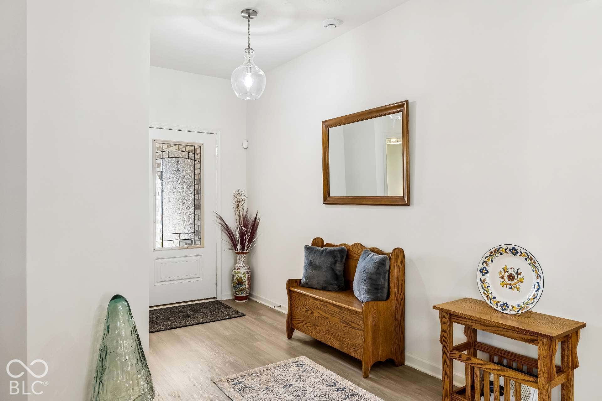 Entryway featuring wood-finish flooring, a white paneled door with decorative glass, and a clear glass pendant light fixture