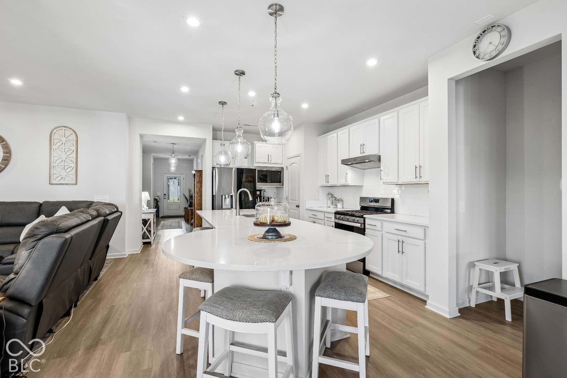Kitchen featuring white cabinetry, a large center island with seating, stainless steel appliances, and wood-finish flooring