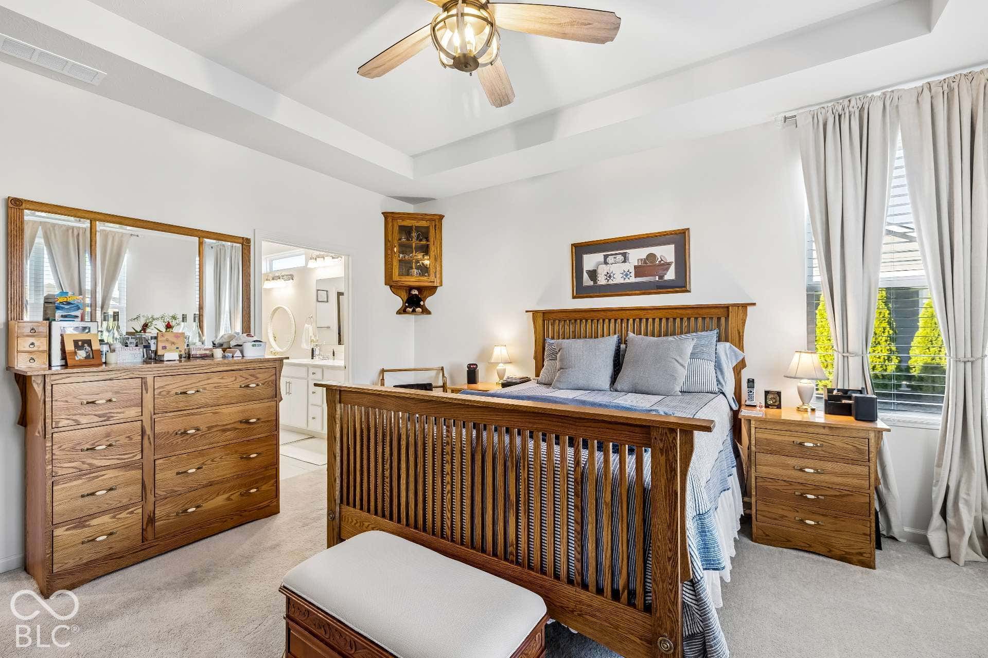 Tray ceiling with a ceiling fan, dual windows, and recessed lighting