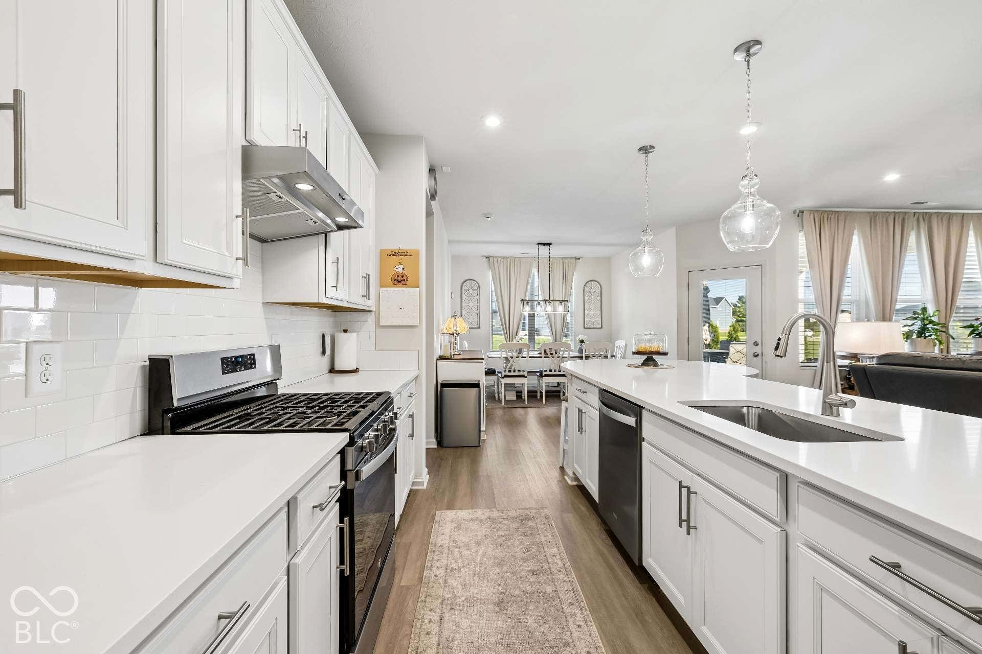 Kitchen featuring white cabinetry, light countertops, subway tile backsplash, and stainless steel appliances