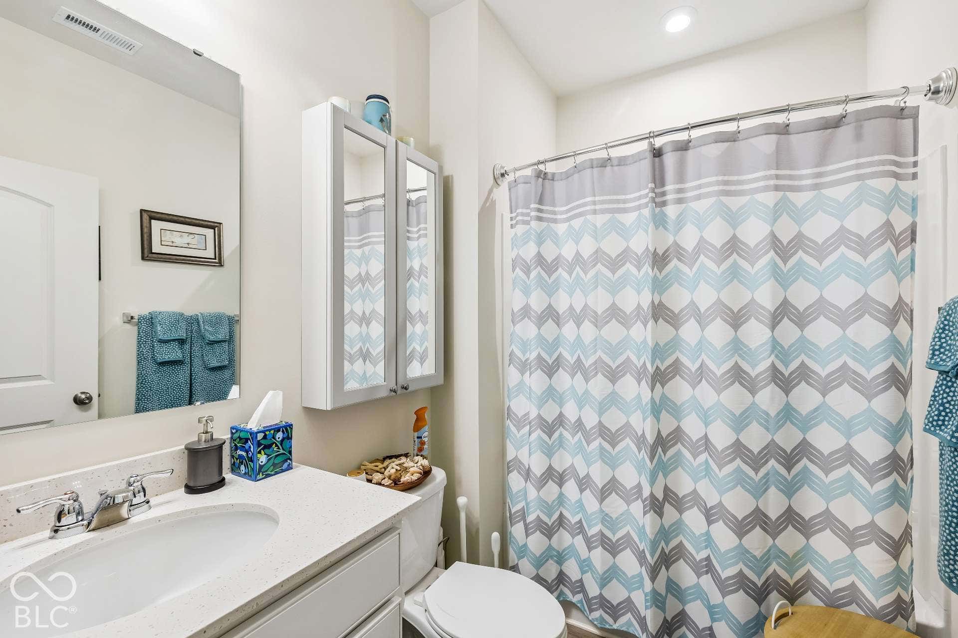 White vanity with a single basin sink and a light-colored countertop