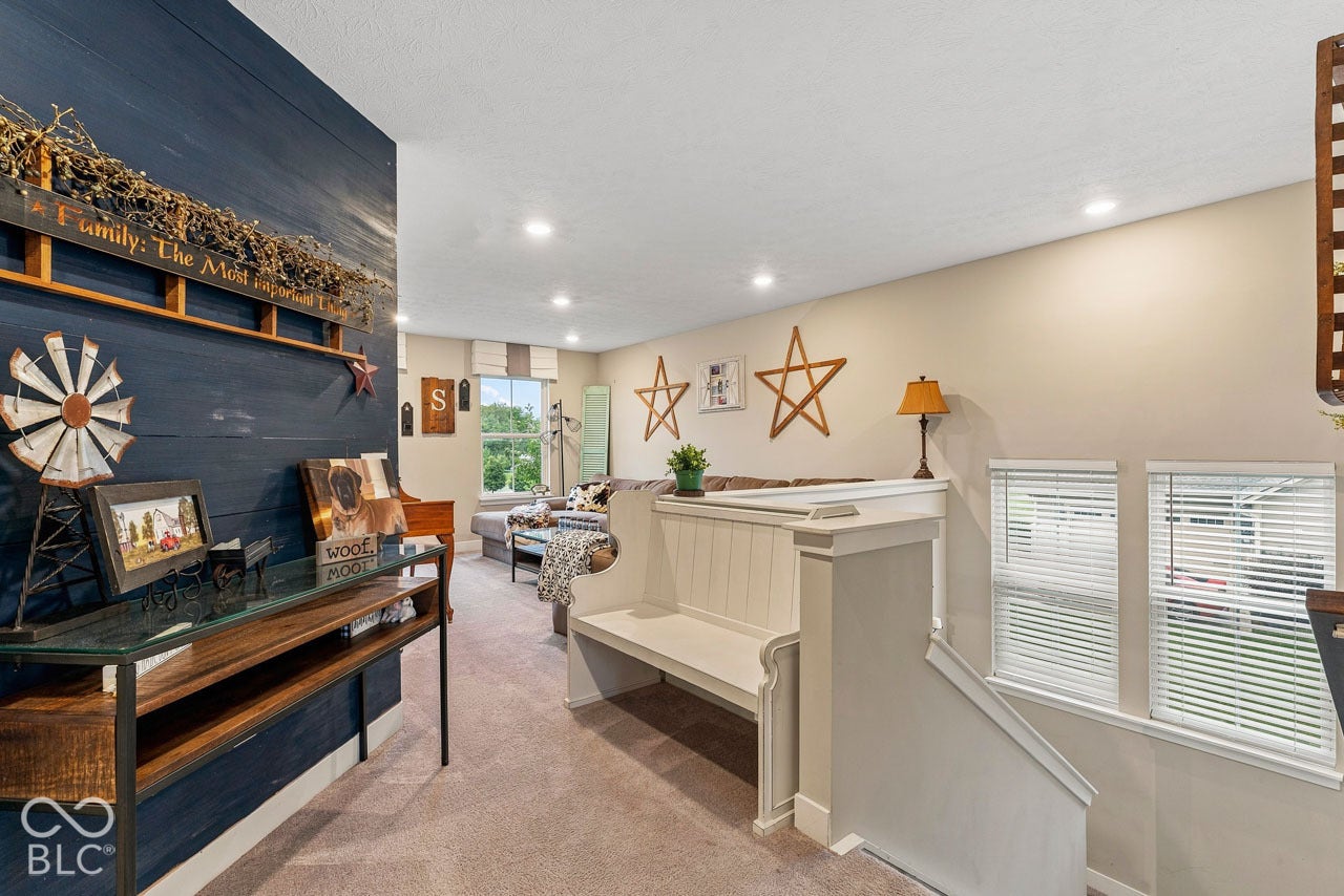 Recessed lighting illuminates the carpeted flooring and light-toned walls