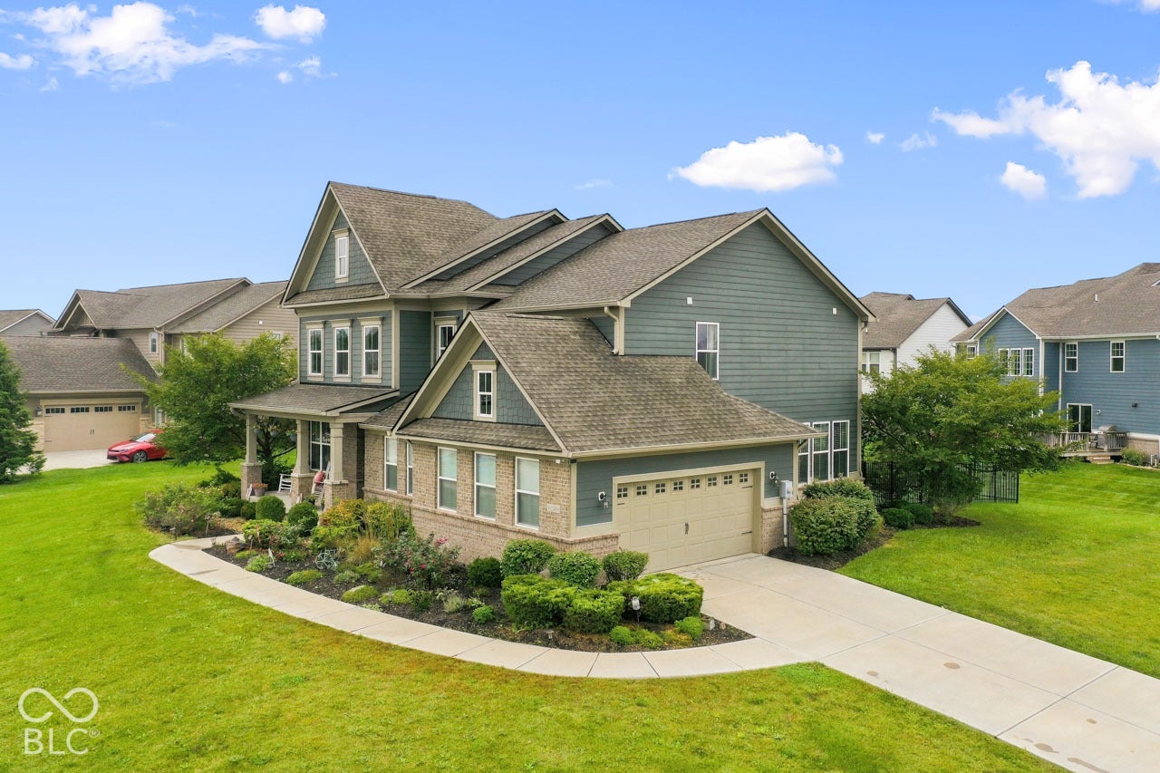 Two-story residence featuring a brick and siding exterior, an attached two-car garage, and a covered front porch