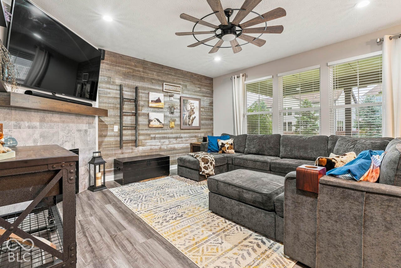 Wood-finish flooring, accent wall with horizontal wood planks, recessed lighting, and a ceiling fan