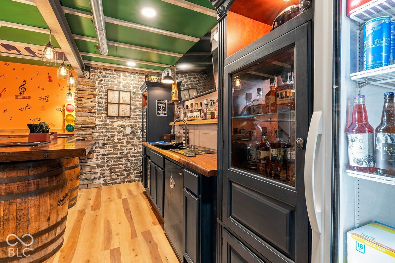 Wood-finish flooring, exposed stone accent wall, butcher block countertops, integrated sink, and built-in glass display cabinetry