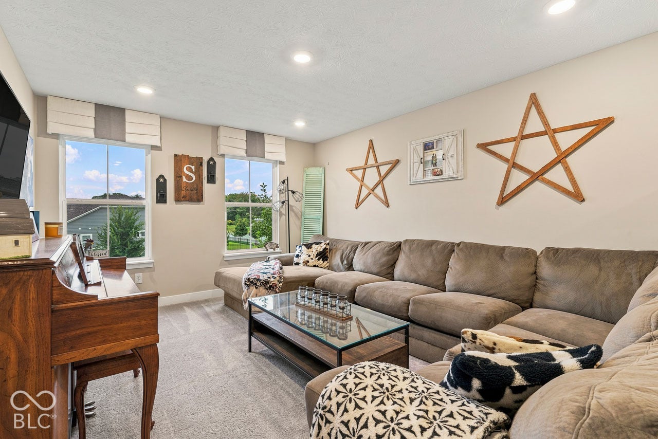 Recessed ceiling lighting, two windows with window treatments, and carpeted flooring
