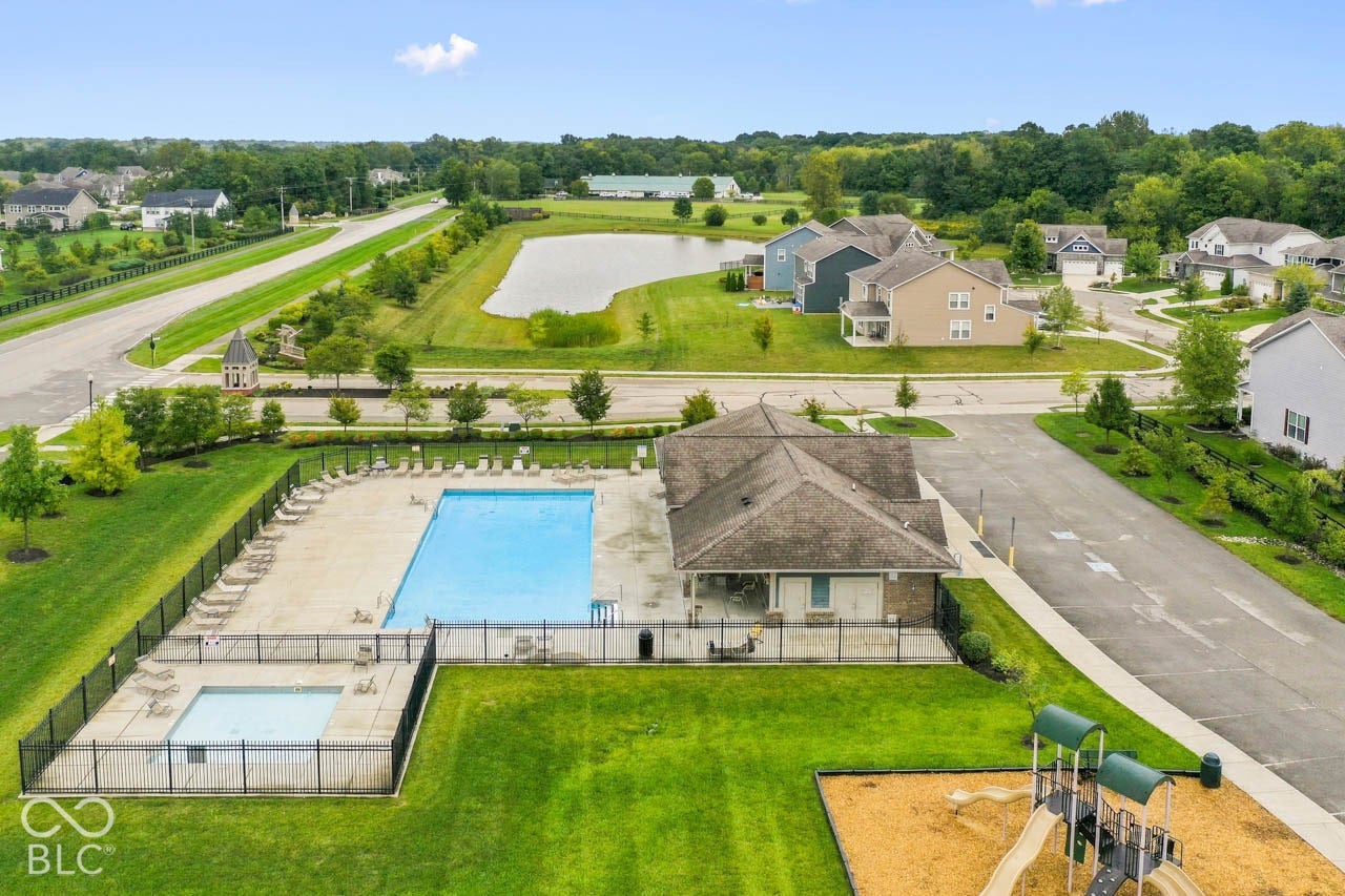 Community pool with an integrated spa, adjacent clubhouse, and fenced playground