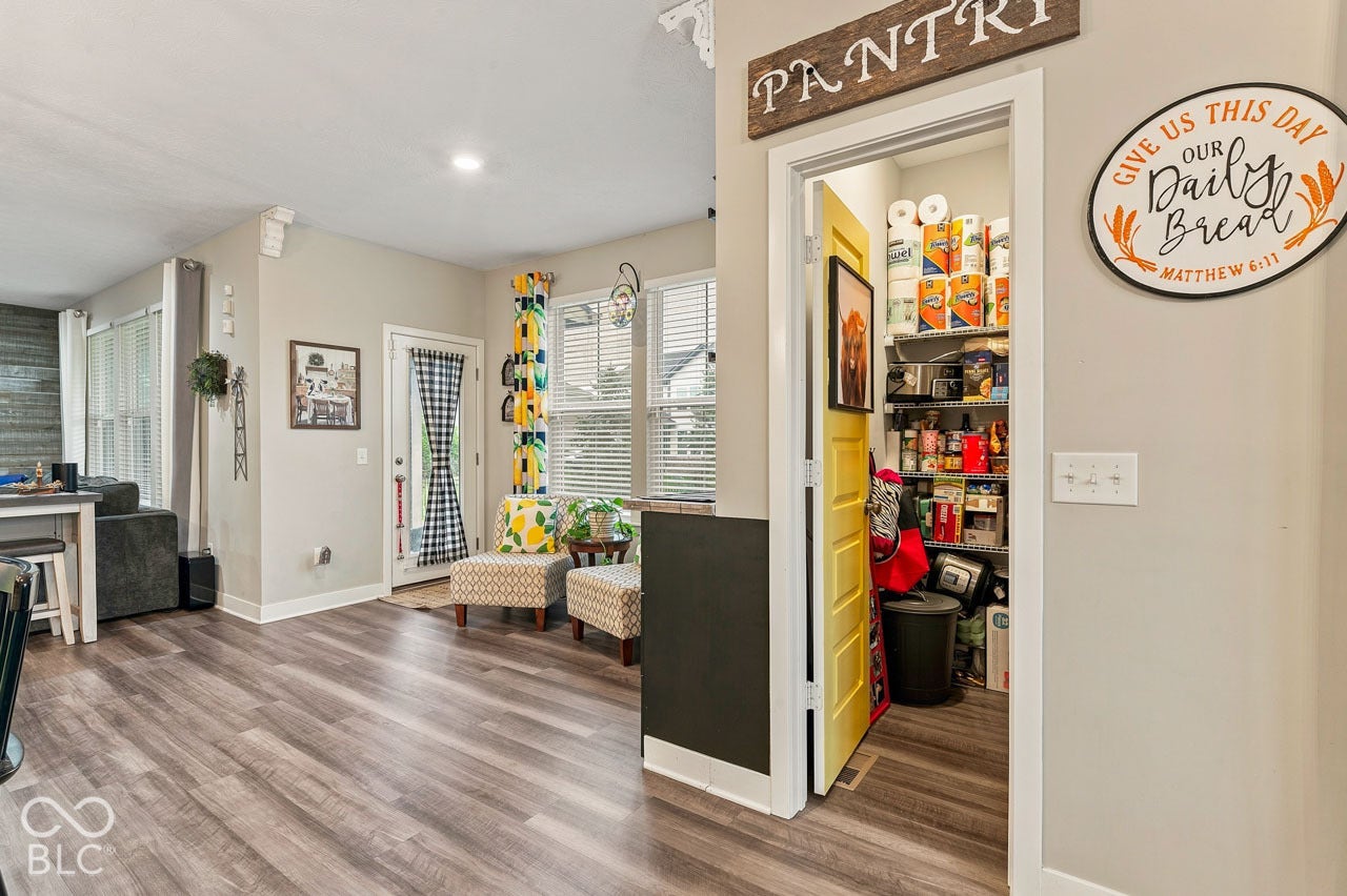 Wood-finish flooring throughout, bright pantry with shelving, white trim, and light-colored walls