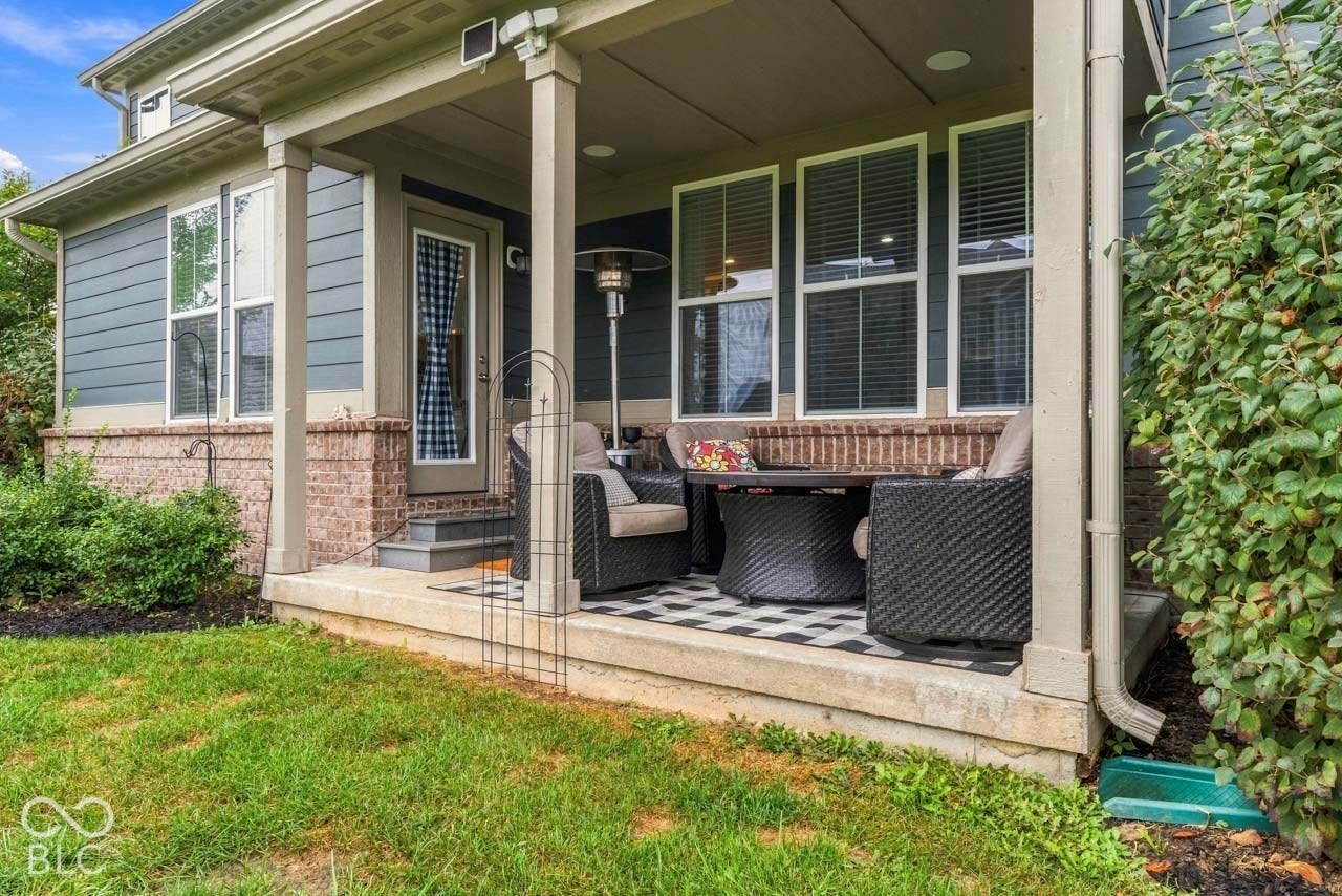 Covered outdoor patio featuring a concrete slab, supporting columns, and a checkered outdoor rug