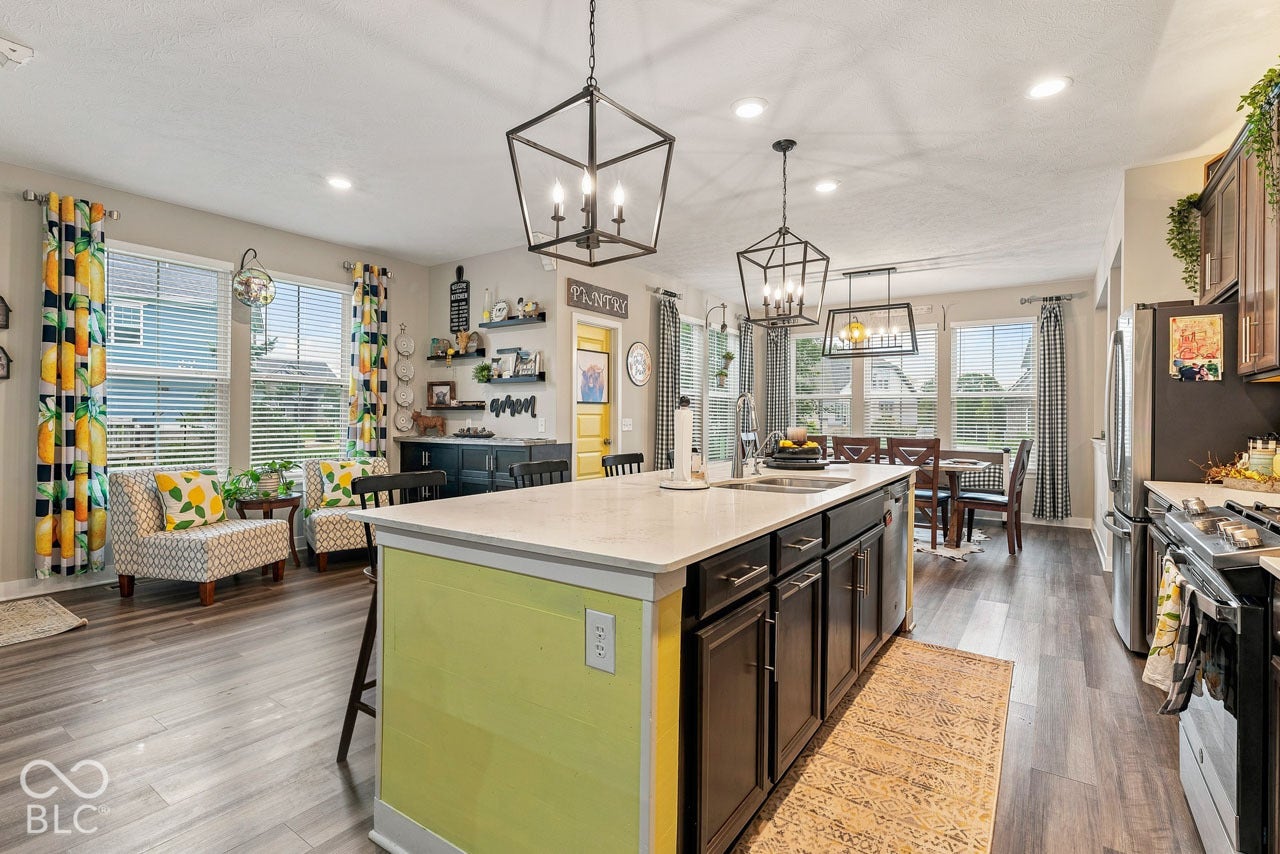 Open-concept living area featuring wood-finish flooring, a kitchen island with a light-colored countertop, and a dining area