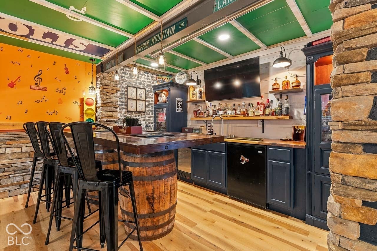 Built-in wet bar featuring dark cabinetry, wood-finish countertops, and a beverage refrigerator