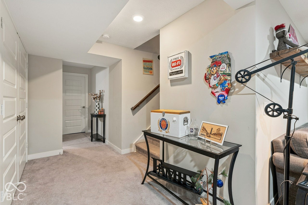 Carpeted flooring throughout, recessed ceiling lighting, paneled interior doors, and a wood-finish staircase handrail