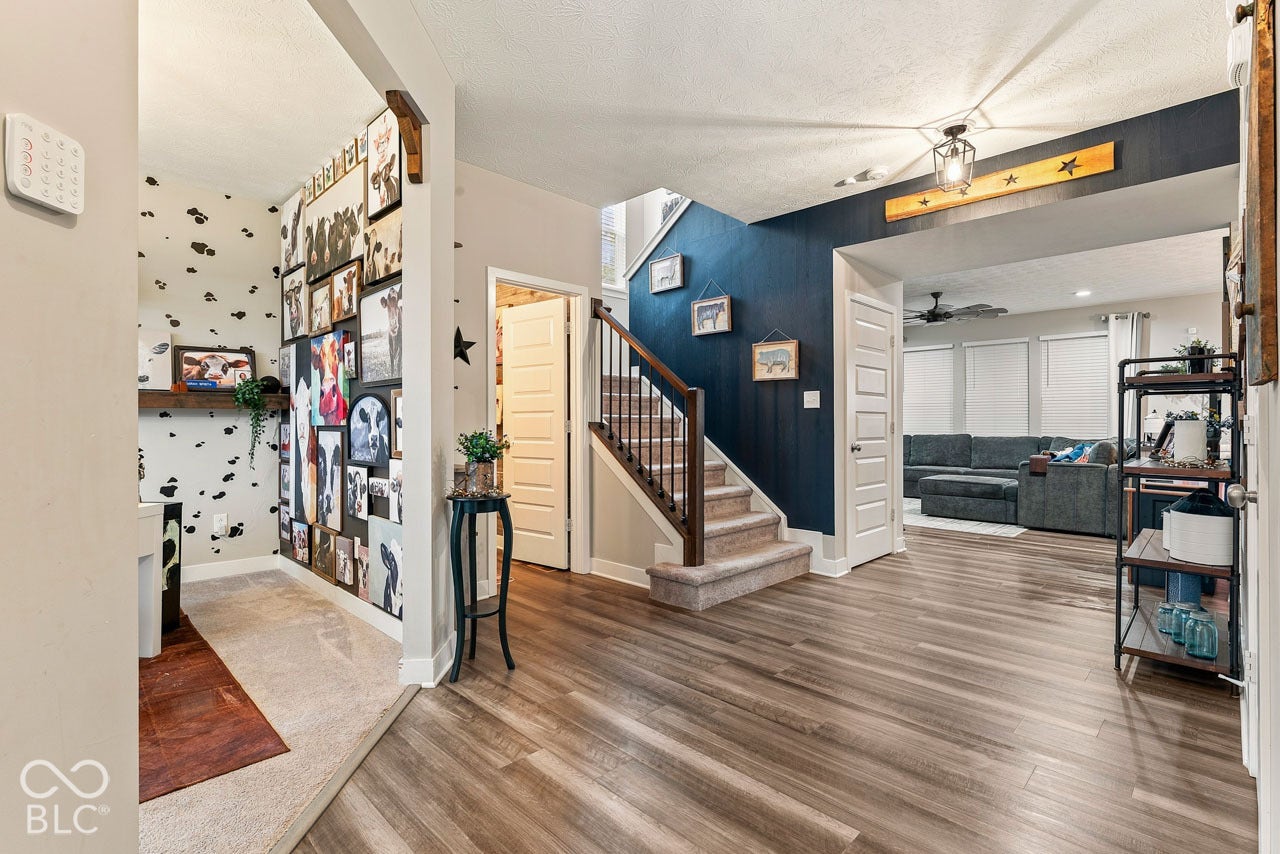 Wood-finish flooring throughout, with a carpeted staircase featuring a wood handrail and wrought iron balusters