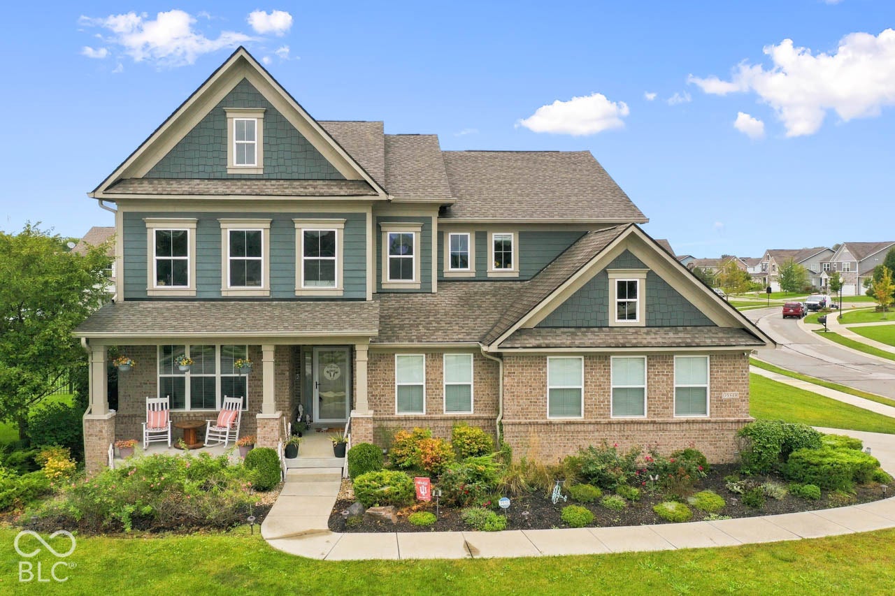 Two-story residence featuring a brick and siding exterior, front porch with columns, gabled rooflines, and a concrete walkway