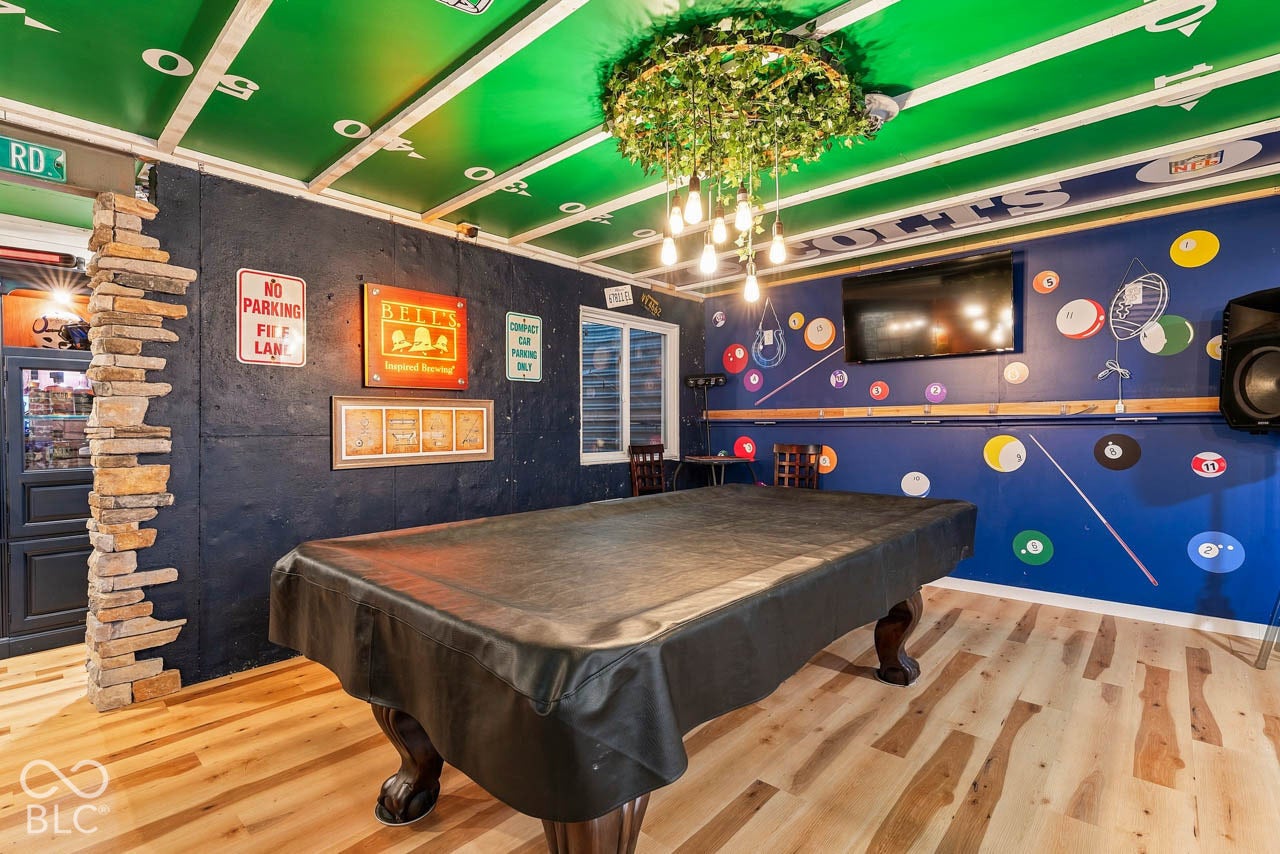 Wood-finish flooring with a decorative ceiling feature, stone-clad pillar, and a wall-mounted display