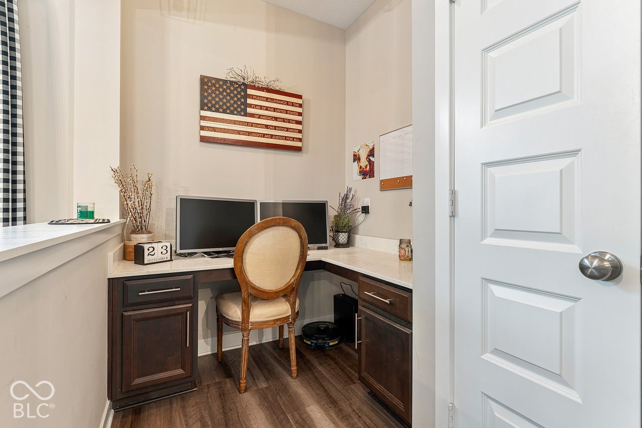 Built-in desk with dark wood-finish cabinetry, light-toned countertop, and wood-finish flooring