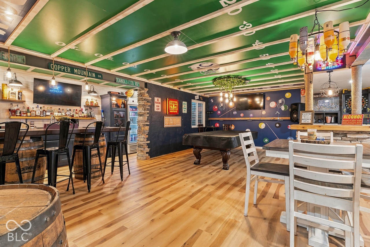 Entertainment space featuring wood-finish flooring, a full bar area, recessed lighting, and a game table