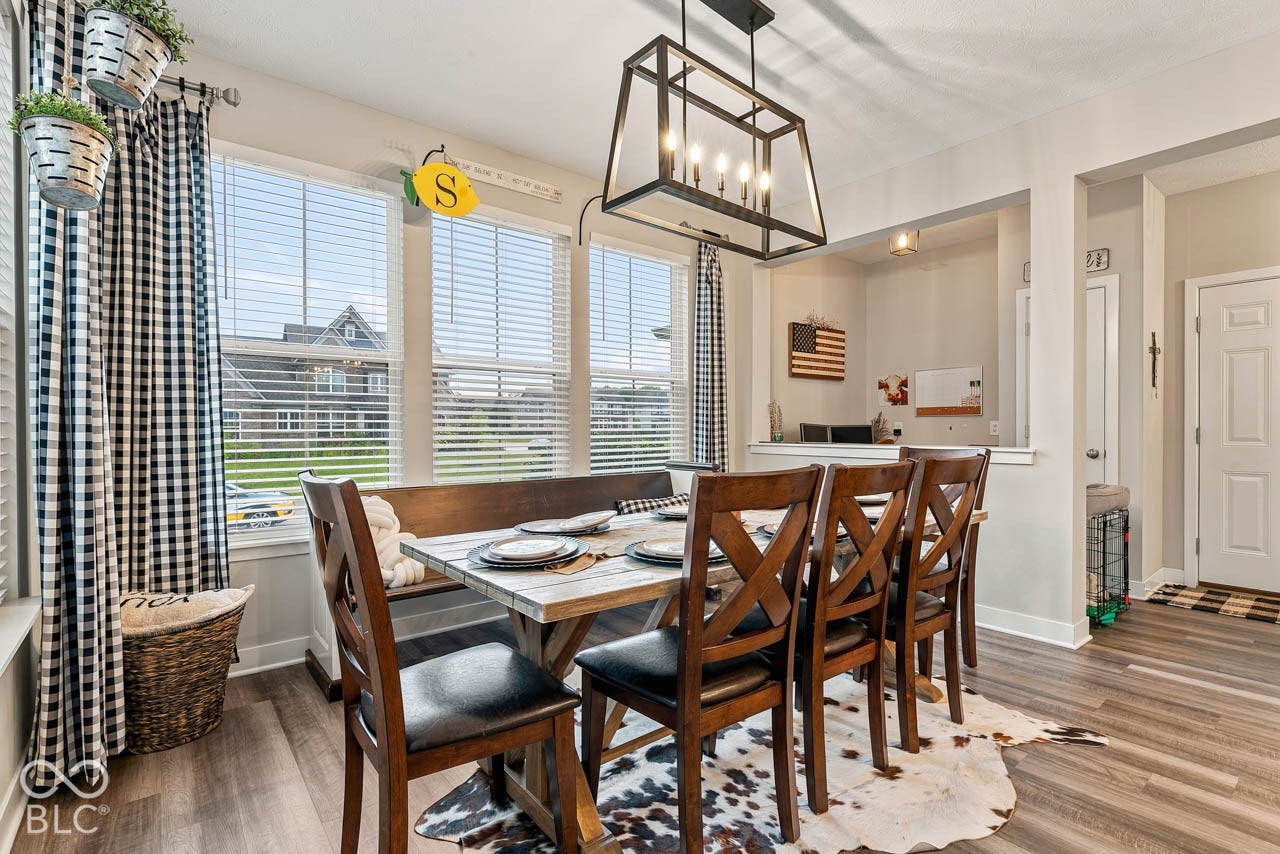 Dining area featuring wood-finish flooring, multiple windows with blinds, a built-in bench, and a rectangular light fixture