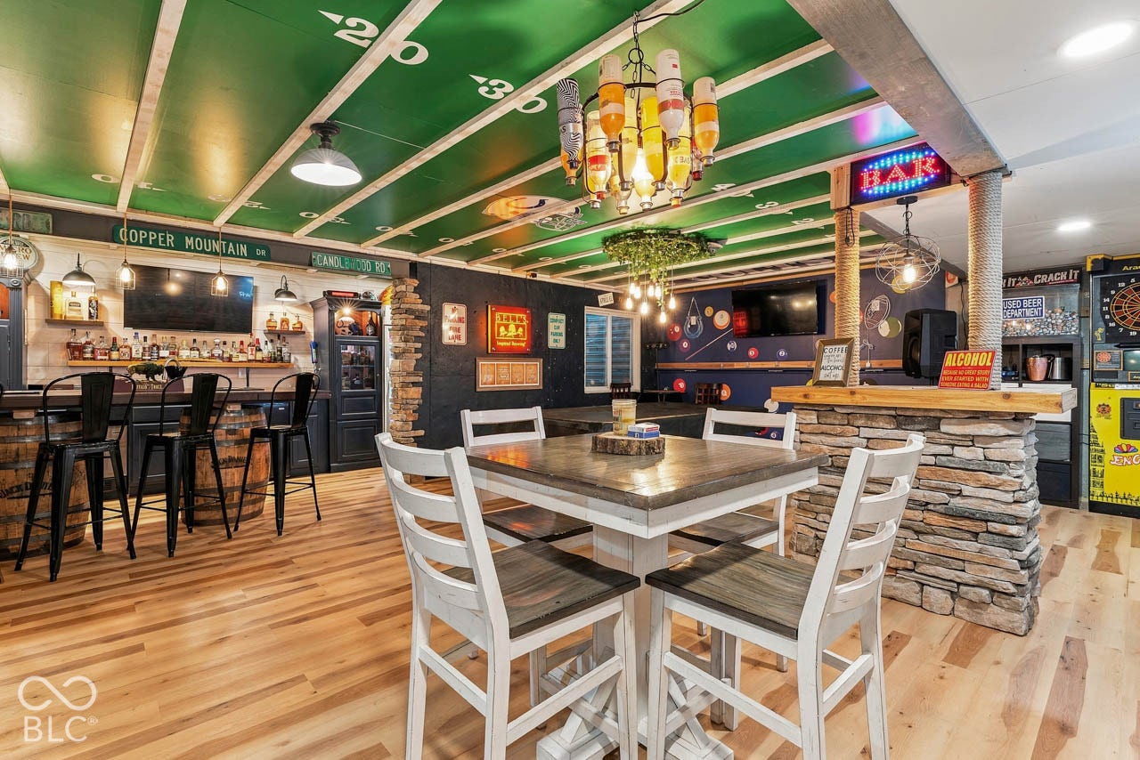 Wood-finish flooring throughout, with a bar area featuring stone accents and a built-in television