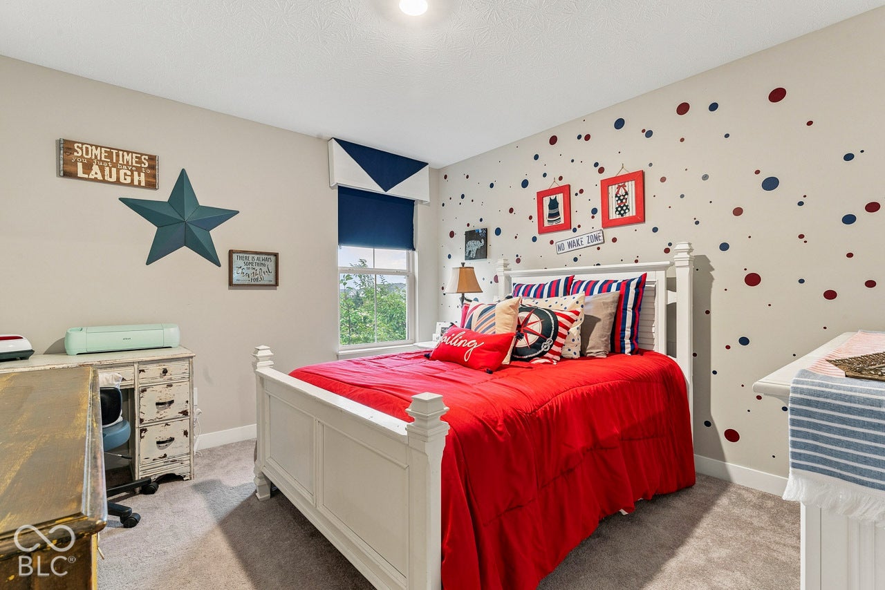 Wall-to-wall carpeting throughout, a window with a roller shade, and a painted accent wall