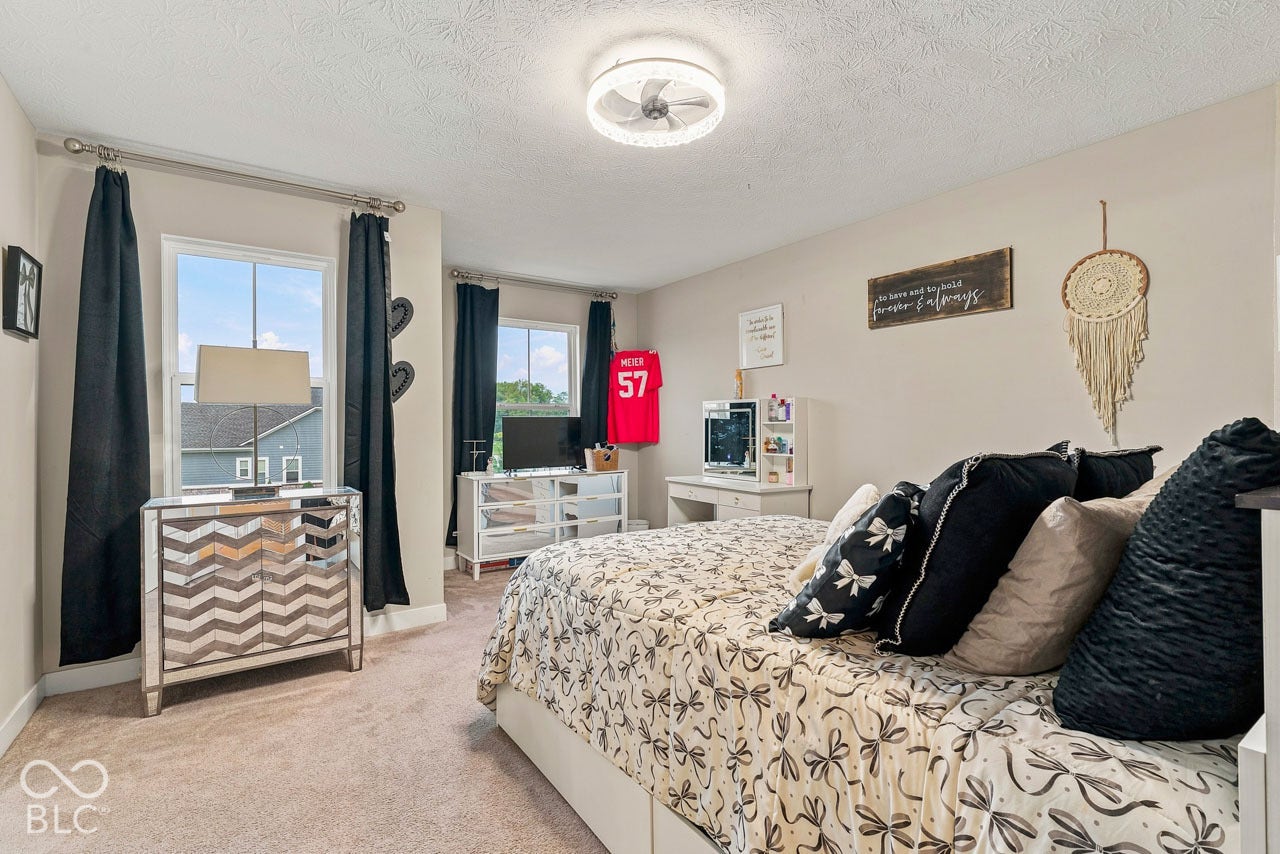 Carpeted flooring, neutral wall color, two windows providing natural light, and a ceiling-mounted light fixture