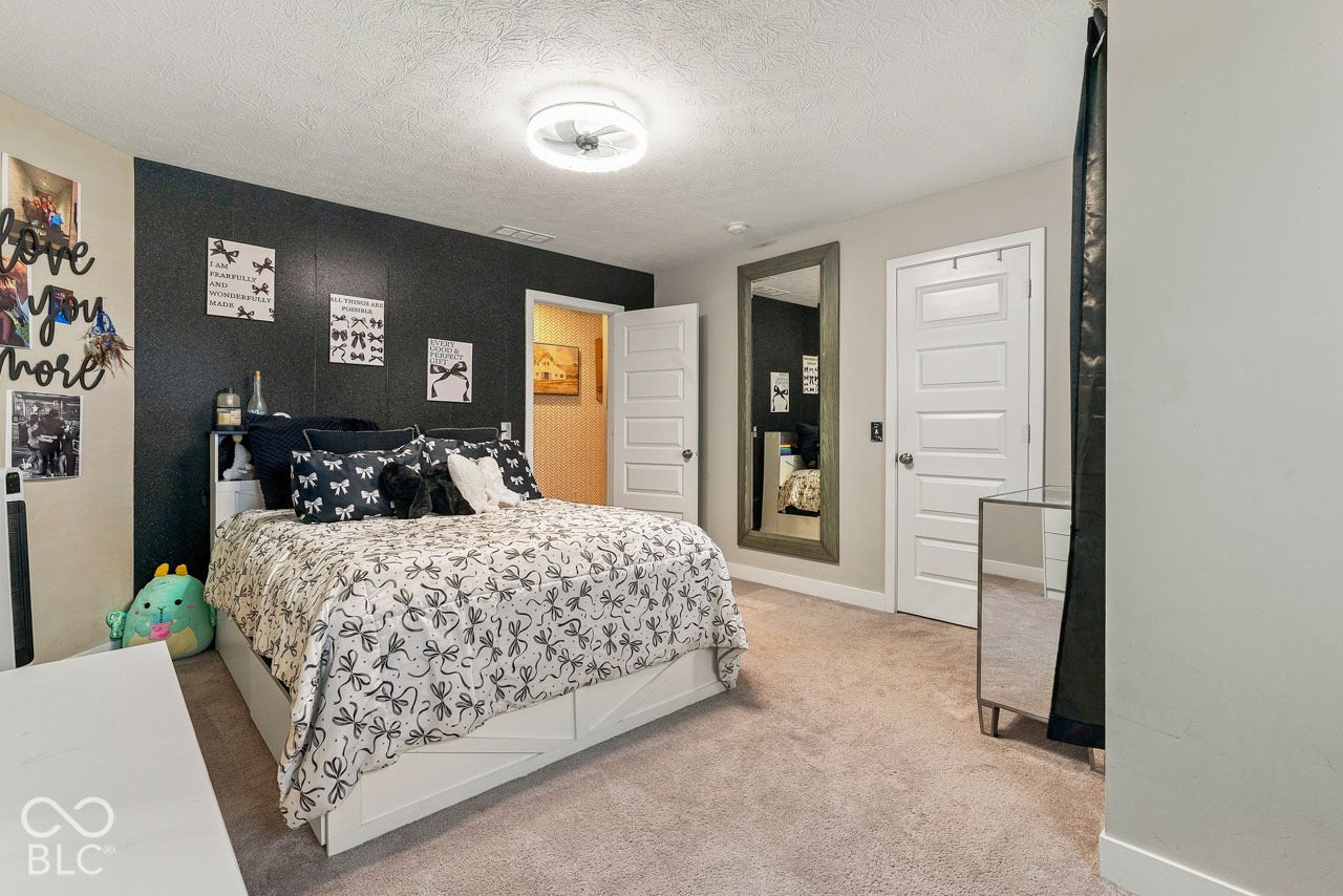 Carpeted flooring, a ceiling-mounted light fixture, and a five-panel interior door