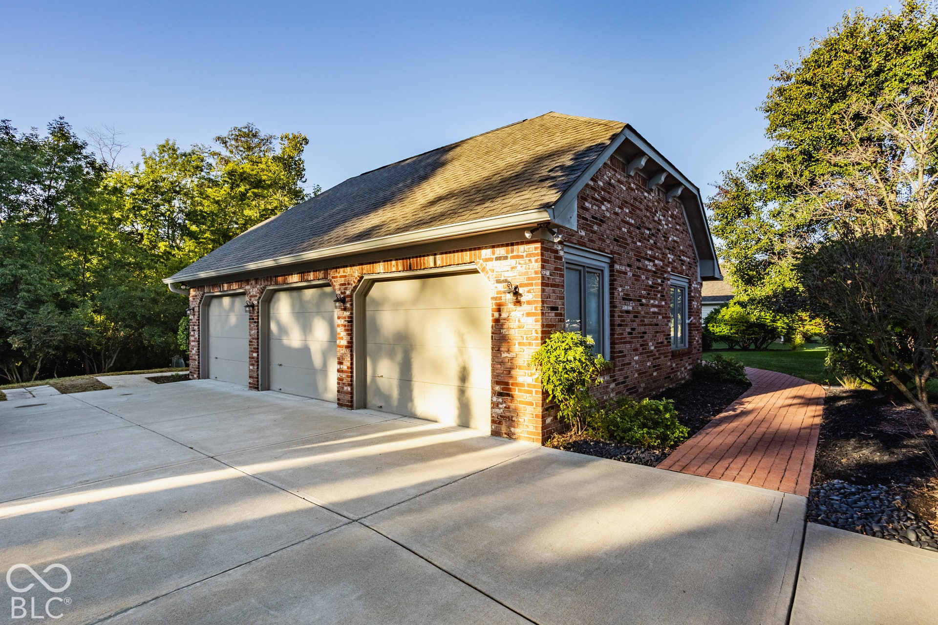 Three car side load garage with a brick exterior and huge concrete driveway