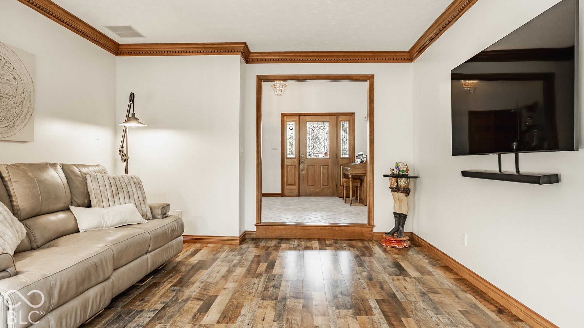 Step down living room with new LVP flooring, freshly painted white walls, and decorative wood trim.