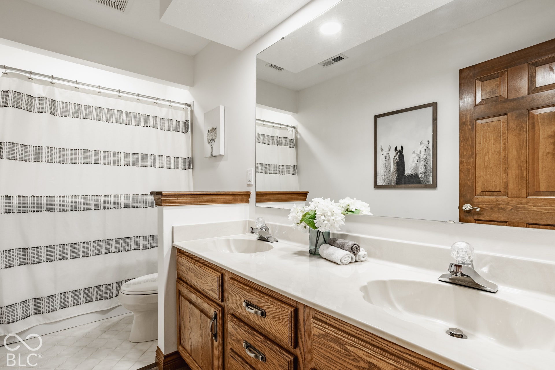 Double vanity with wood-finish cabinetry, white countertop, and integrated sinks