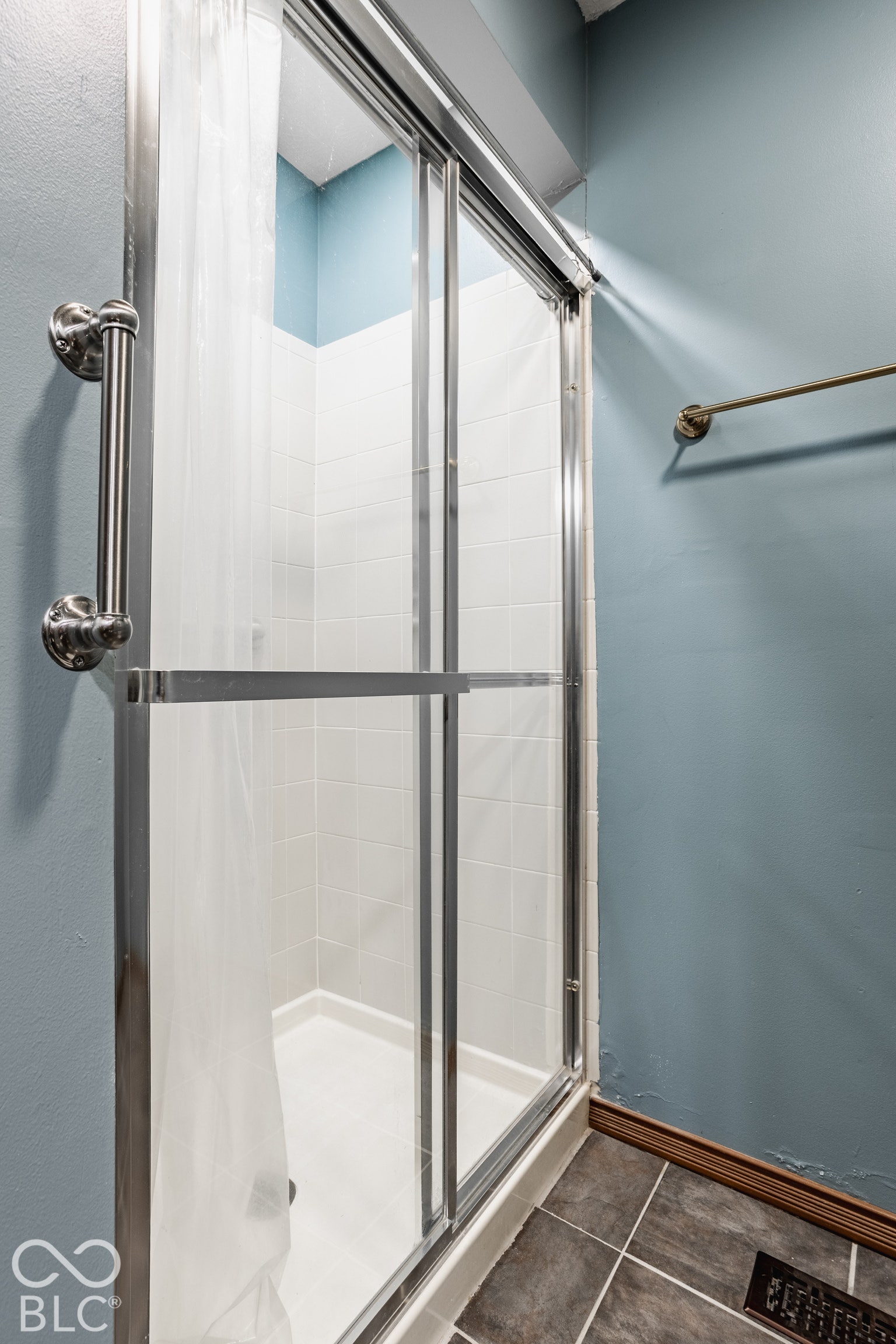 Sliding glass shower enclosure with chrome hardware shares the room with a comode.