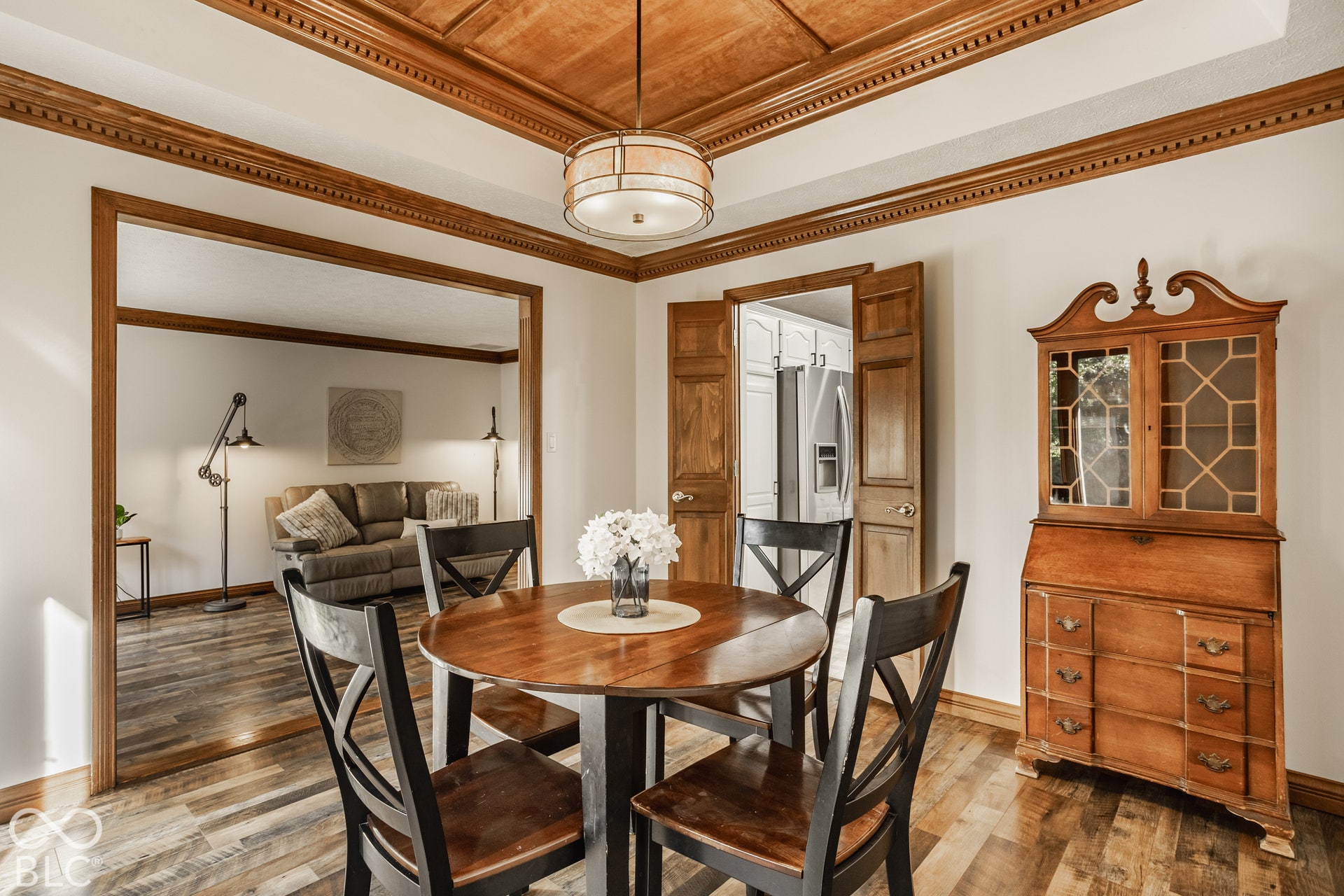 Dining room with new LVP flooring, wood tray ceiling, wood trim, freshly painted white walls, and a newer drum pendant light fixture