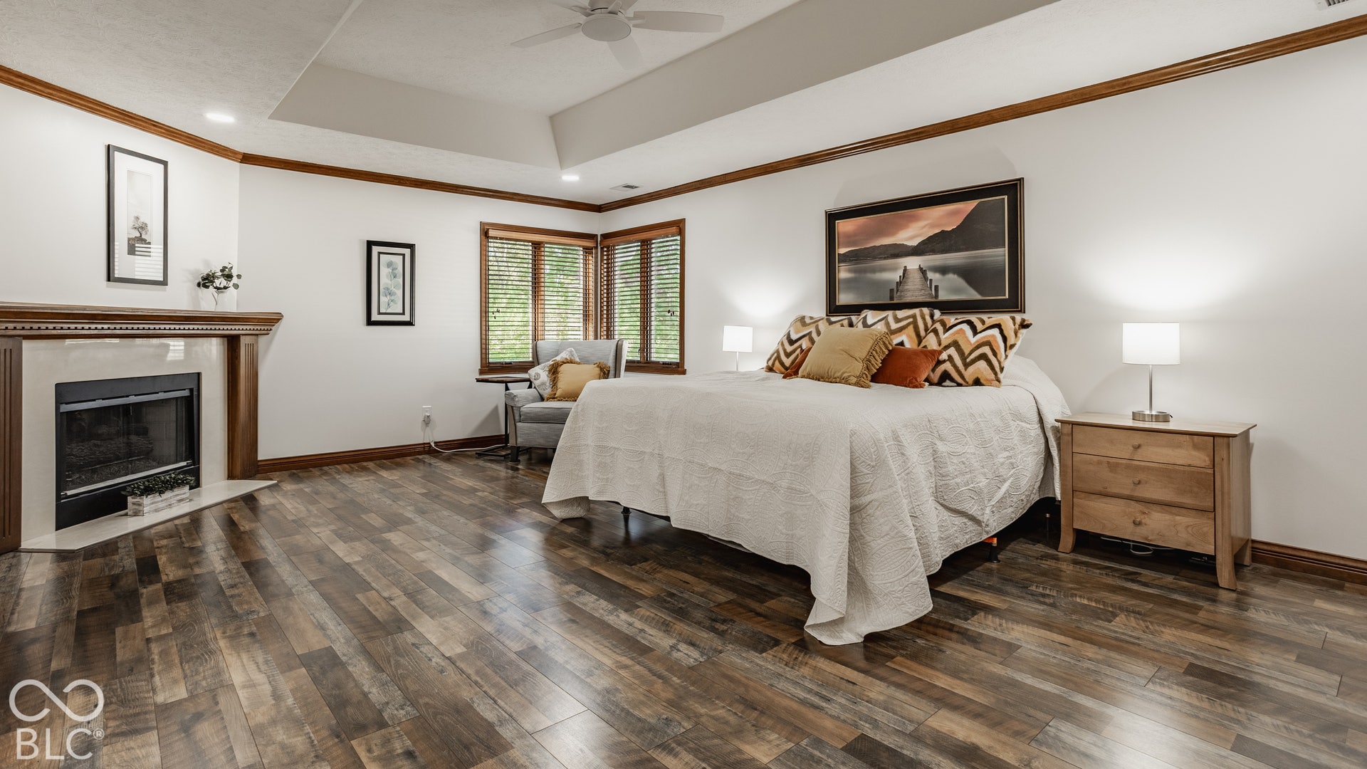 Primary suite with gas fireplace with mantel surround, new LVP flooring, tray ceiling, bay window, and recessed lighting