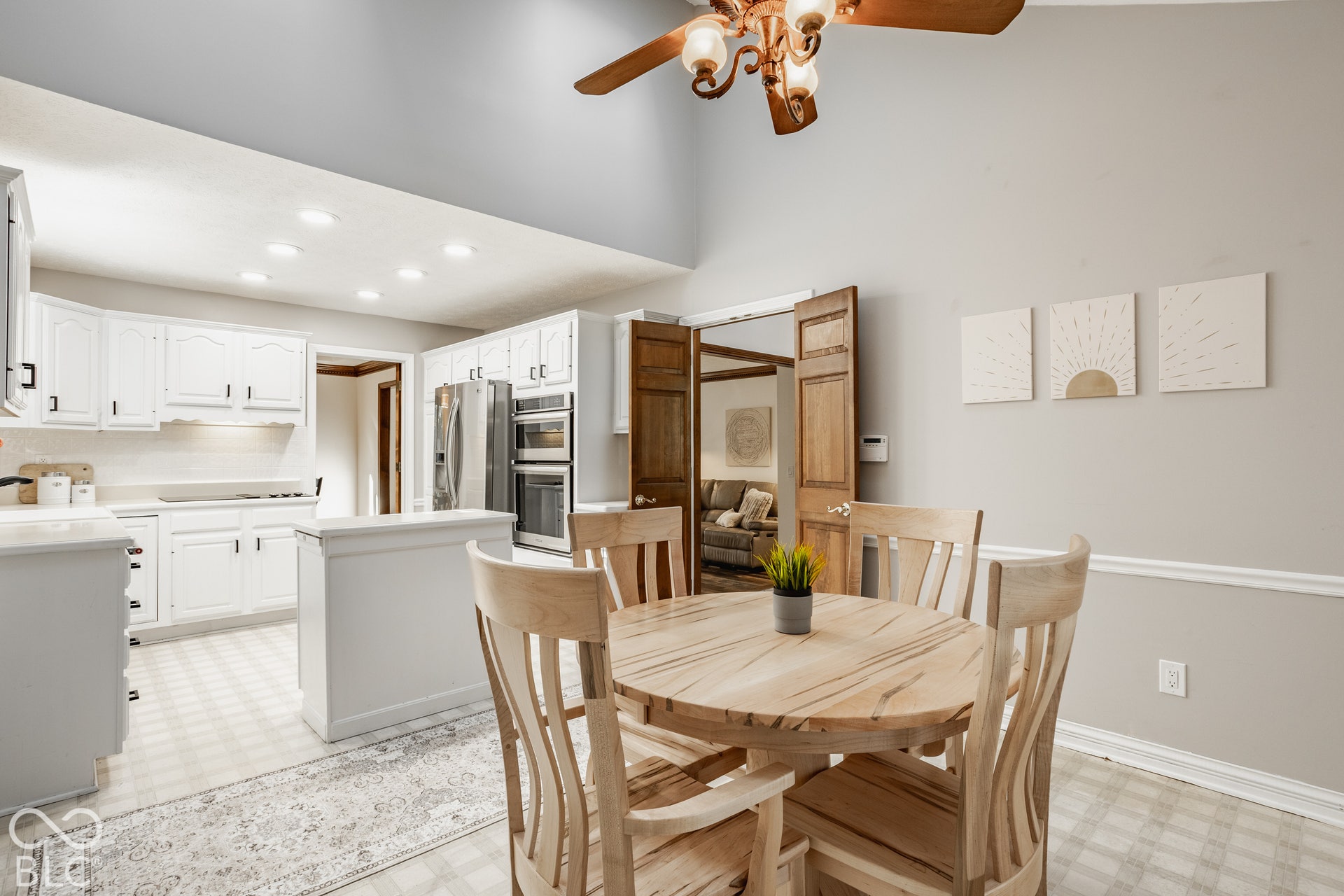 Eat in kitchen with vaulted ceiling with a ceiling fan, white kitchen cabinetry, stainless steel convection oven and microwave, and a center kitchen island