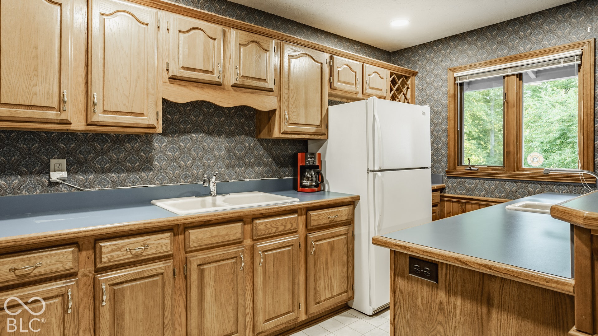 Light wood-finish cabinetry, built-in wine rack,  and a double basin sink in basement apartment