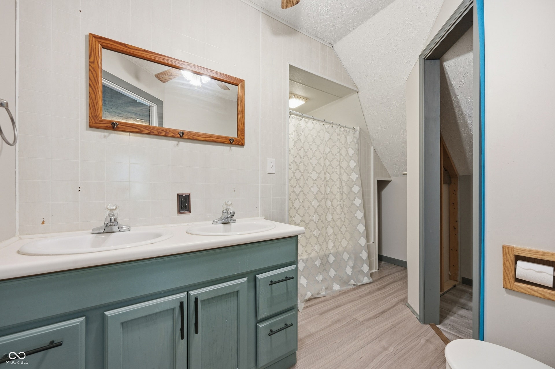 Dual basin vanity with a wood-finish framed mirror and paneled walls