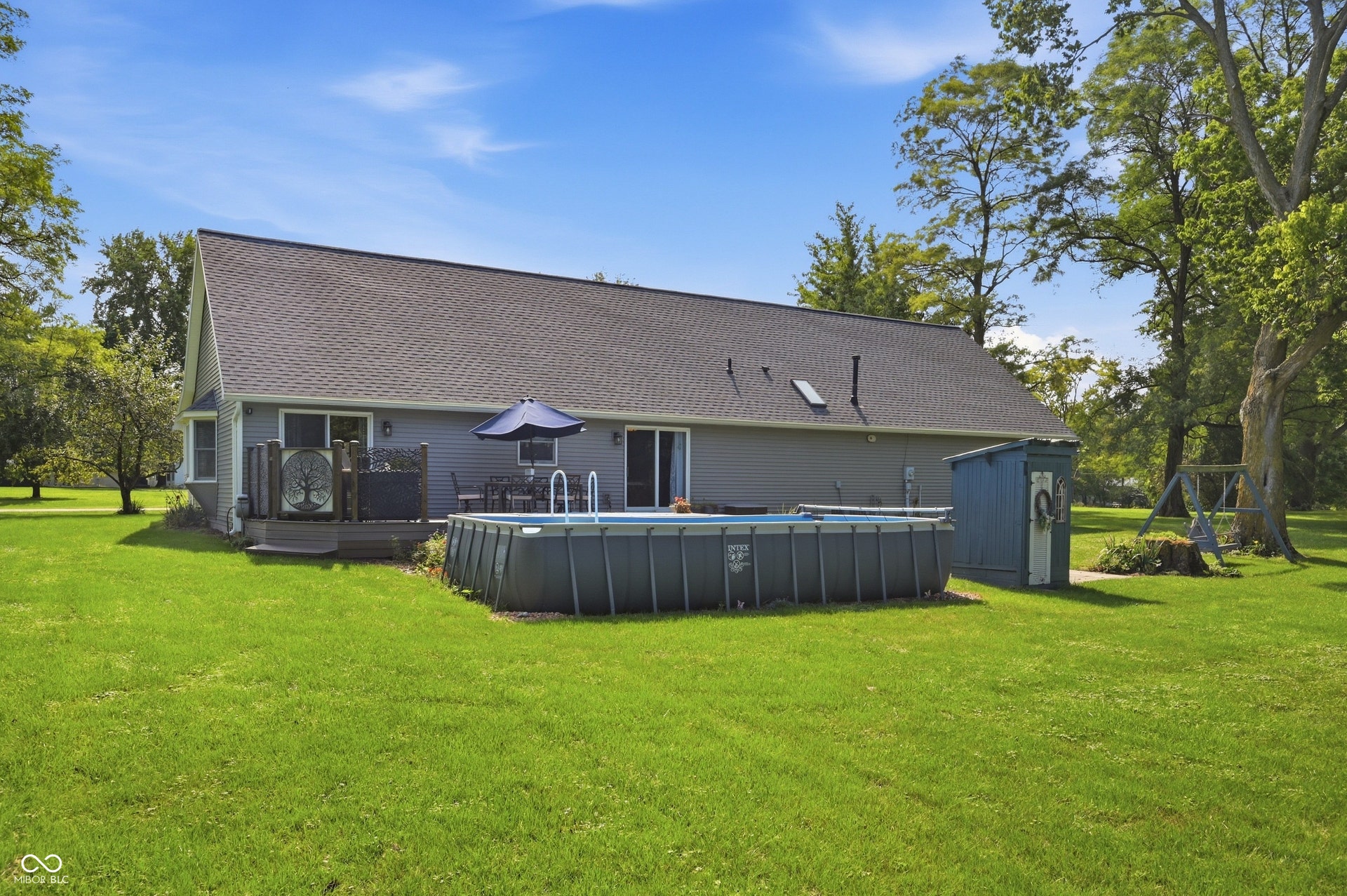 Expansive backyard featuring an above-ground pool, a wooden deck, and a storage shed