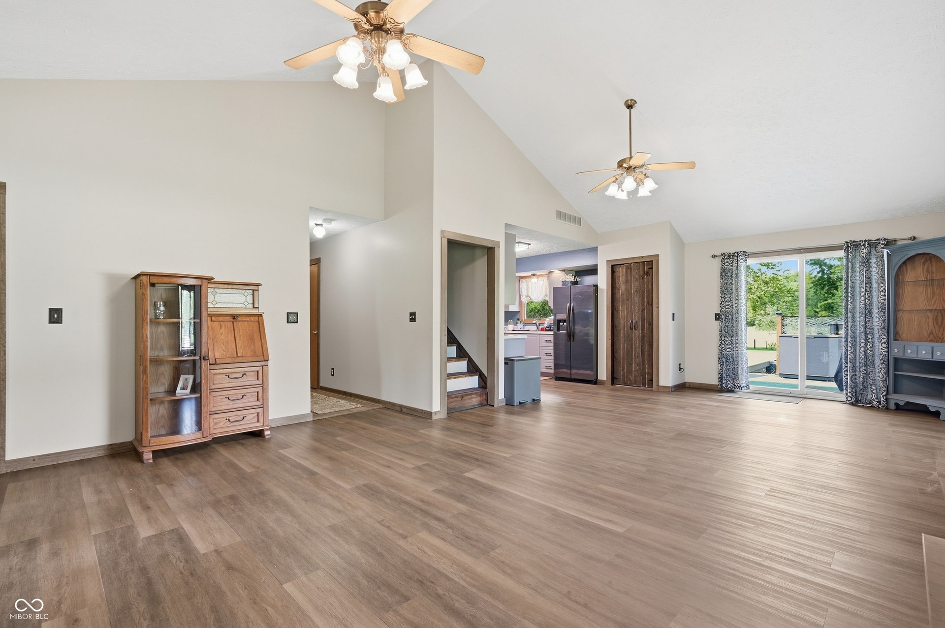 Vaulted ceilings with ceiling fans, wood-finish flooring, sliding glass door, and neutral wall tones