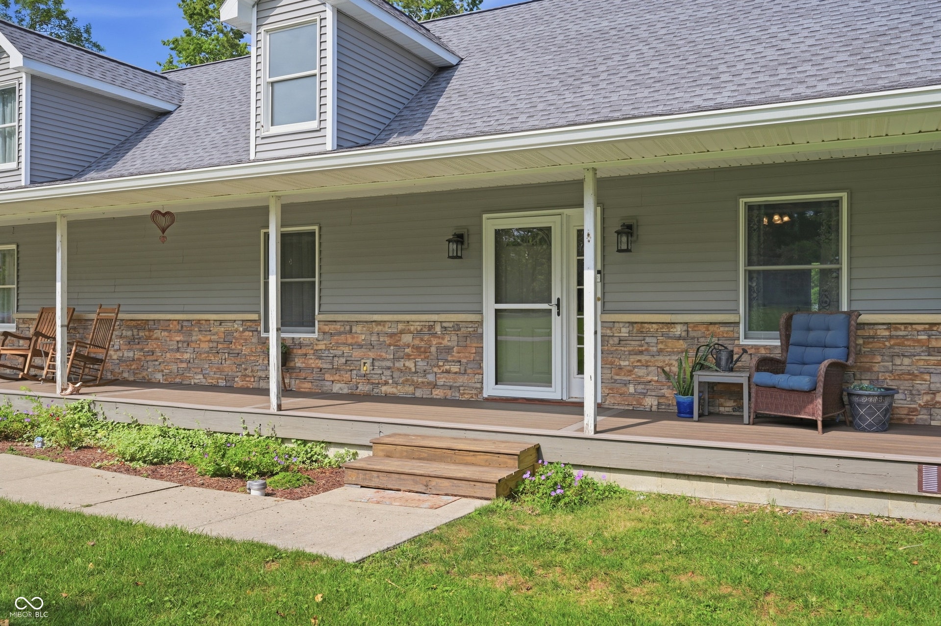 Stone veneer accents on the facade complement the gray siding