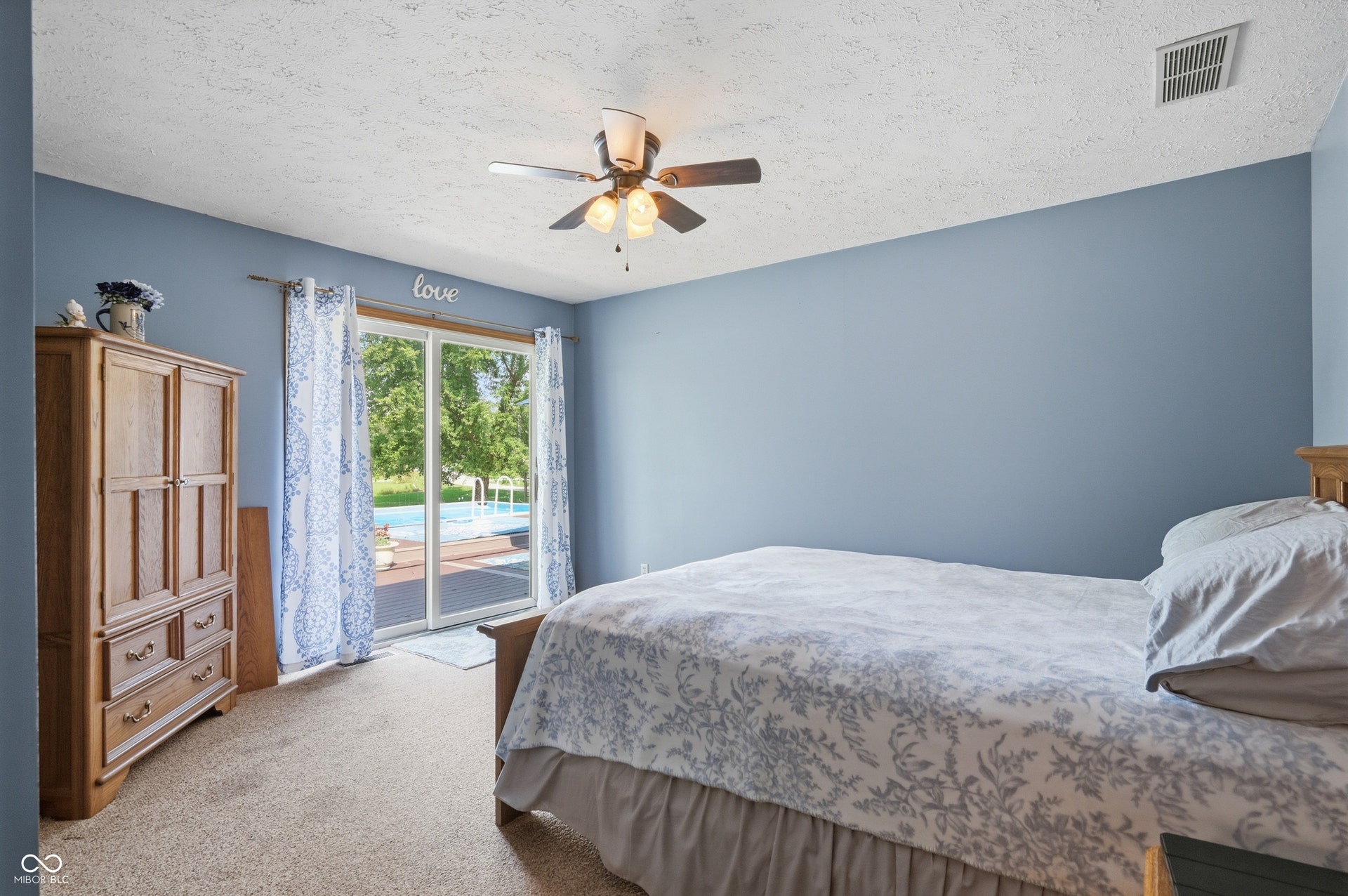 Sliding glass door leading to outdoor space, ceiling fan with integrated lighting, textured ceiling, and carpeted flooring