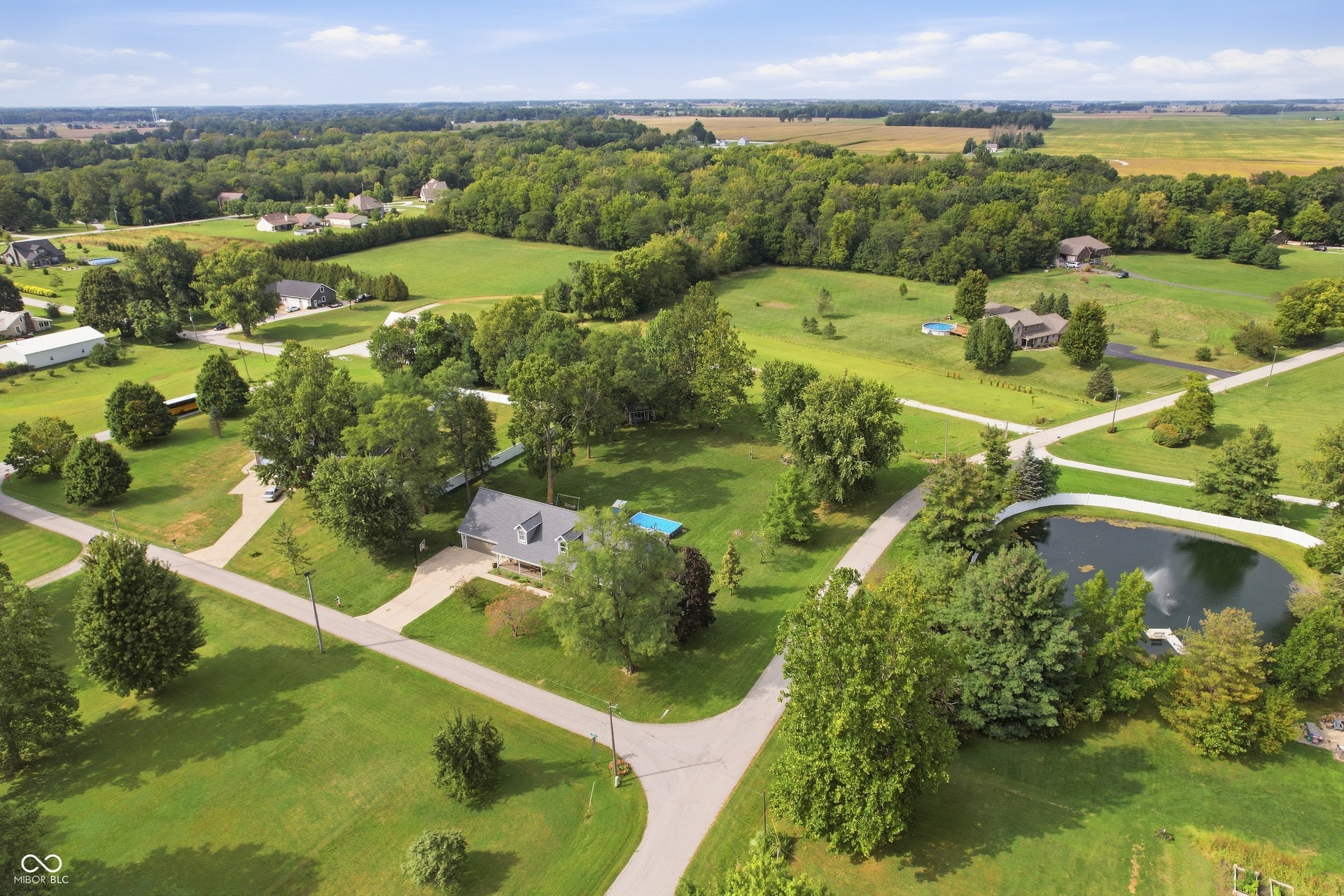 Expansive grounds featuring a private pond with a fountain, mature trees, an inground swimming pool, and a large driveway