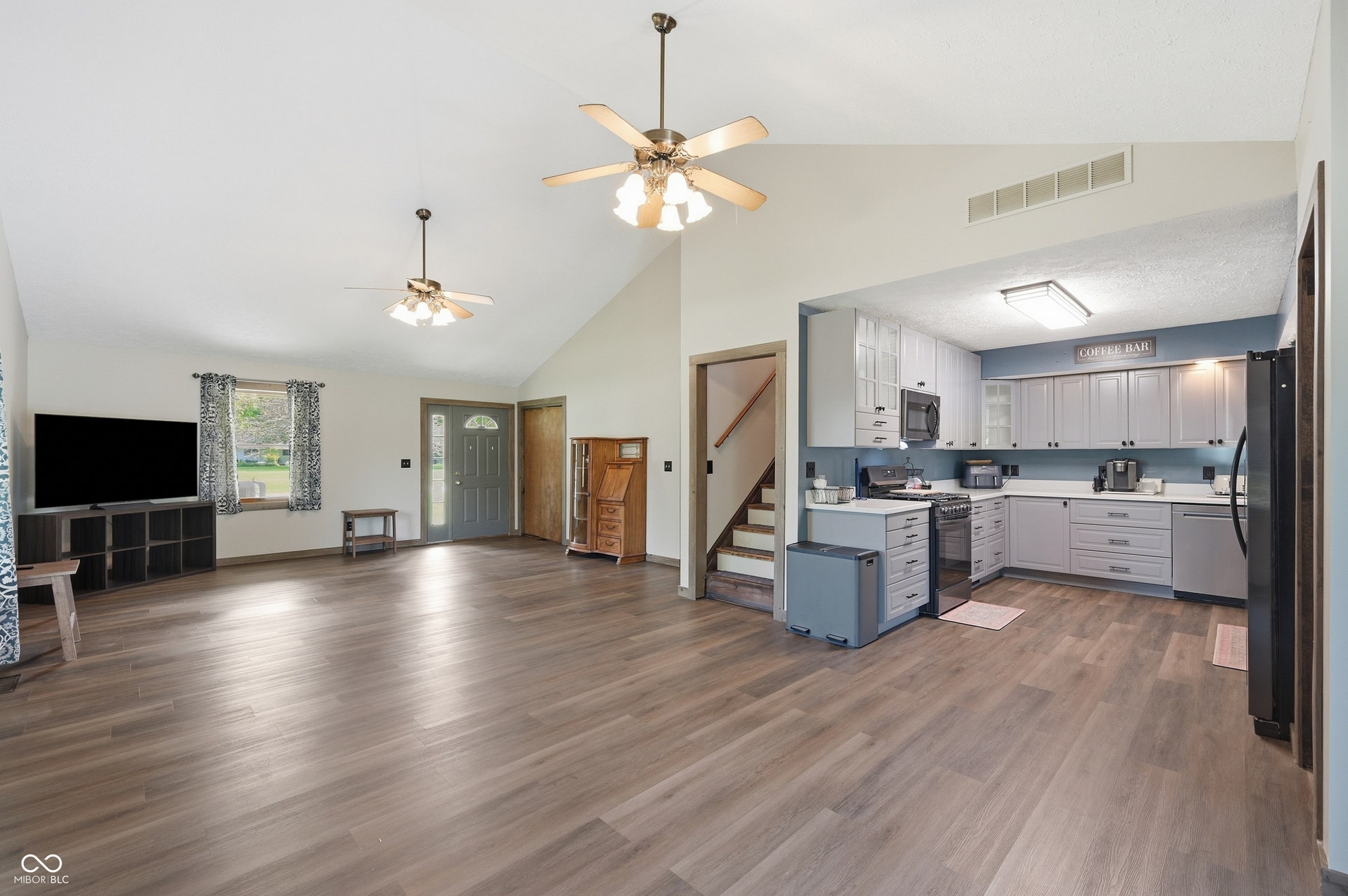 Open-concept living space featuring wood-finish flooring, vaulted ceilings, and ceiling fans