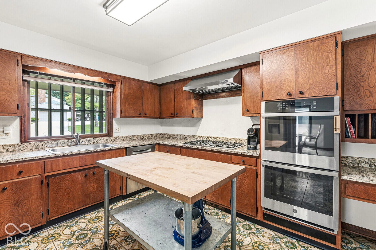 7622 Silverpine Court, Indianapolis, IN 46250 Kitchen has preserved cabinetry, BOOS island cart, and new stainless-steel appliance suite with a gas cooktop and double oven.