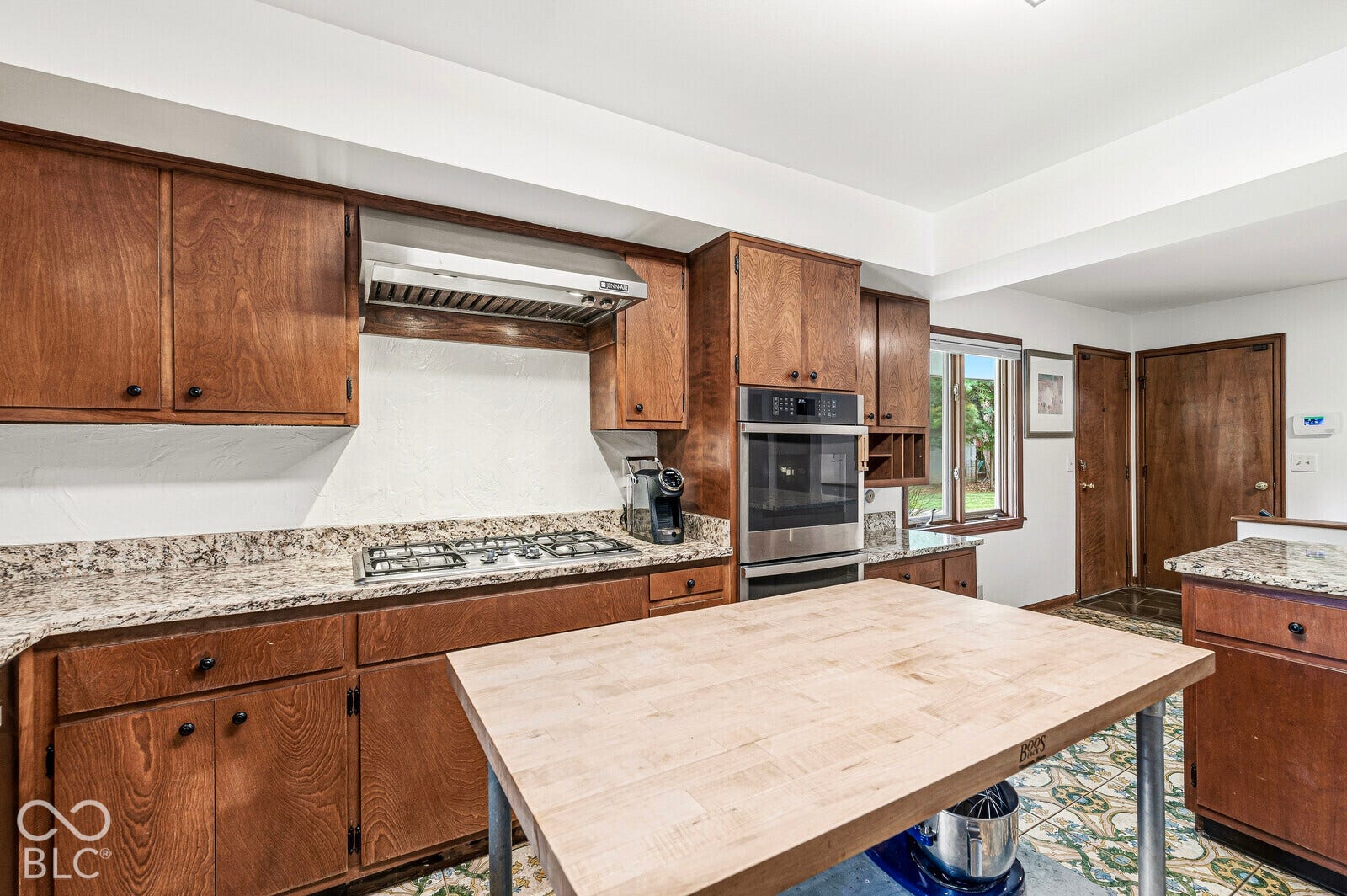 7622 Silverpine Court, Indianapolis, IN 46250 Kitchen has preserved cabinetry, BOOS island cart, and new stainless-steel appliance suite with a gas cooktop and double oven.