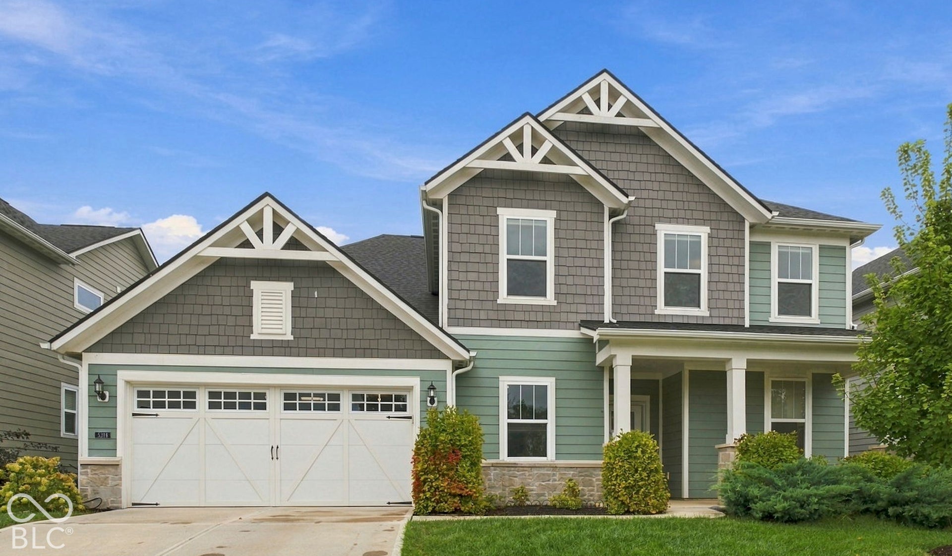 Craftsman-style exterior with stone veneer accents, multi-tone siding, decorative gable trusses, a covered porch with columns, and an integrated two-car garage
